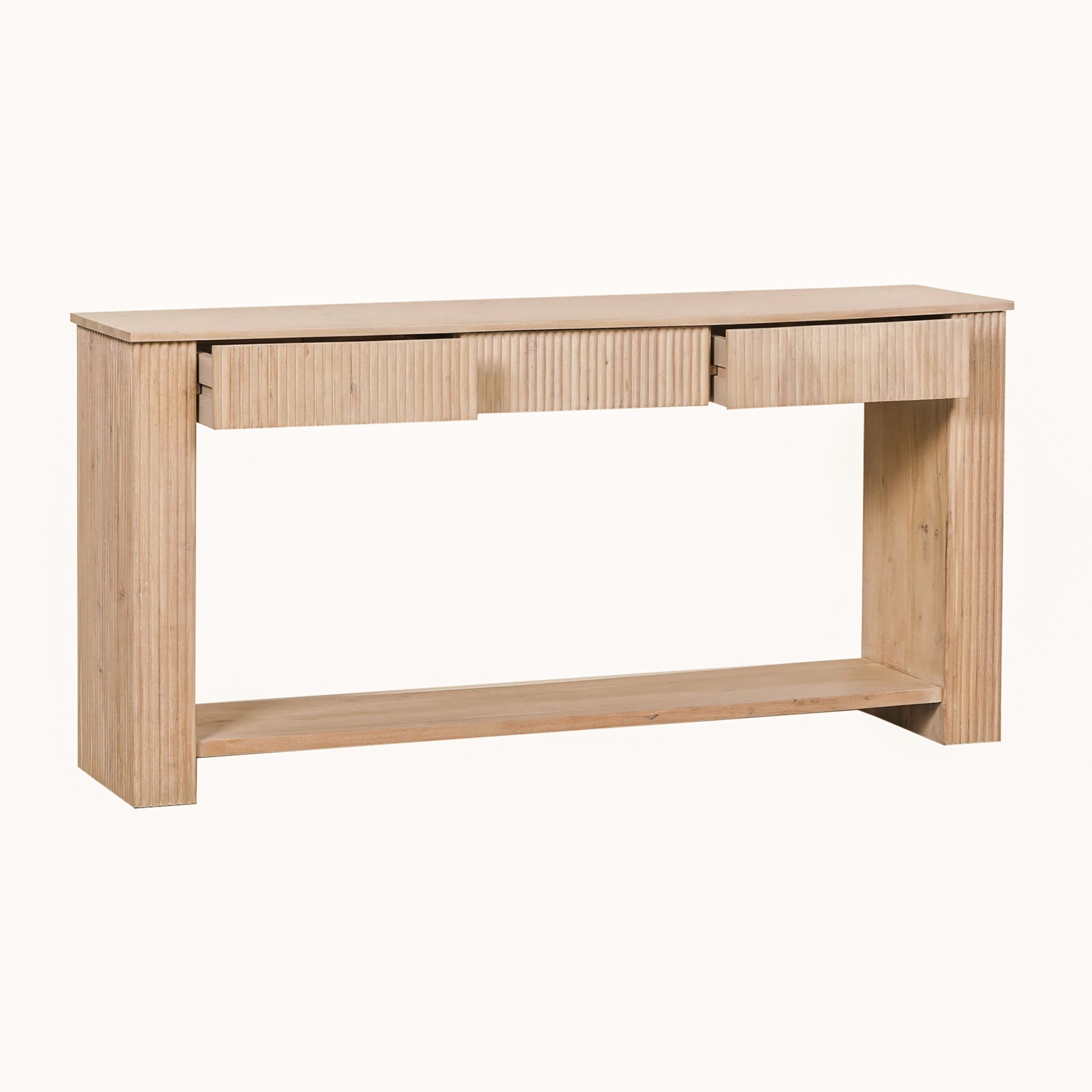 Camille acacia wood console table with three fluted drawers and a full-width lower shelf, shown from an angled front view in its light bleached washed wood finish.