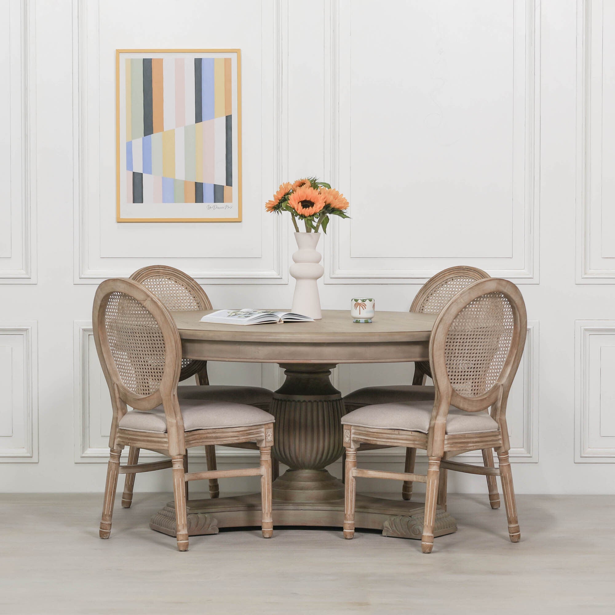 Camille Round Pedestal Dining Table 150cm for 6 in Rustic White Cedar Wood styled with upholstered rattan dining chairs, fresh flowers and decorative accessories, showcasing the spacious round tabletop, carved fluted pedestal base and timeless French country farmhouse dining room design.
