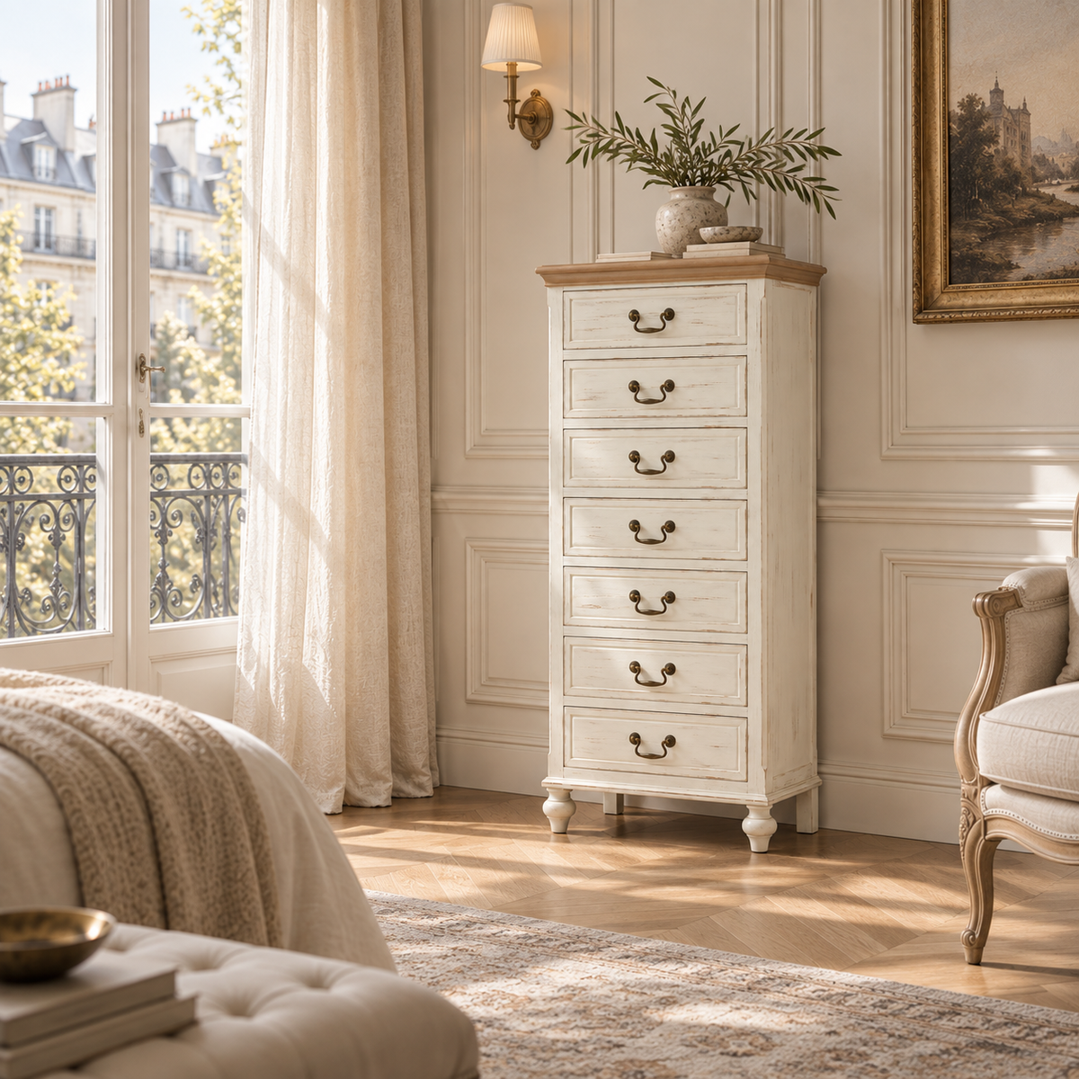 Coralie washed ivory 7 drawer tallboy with natural wood top in a Parisian bedroom with window, armchair and wood floor.