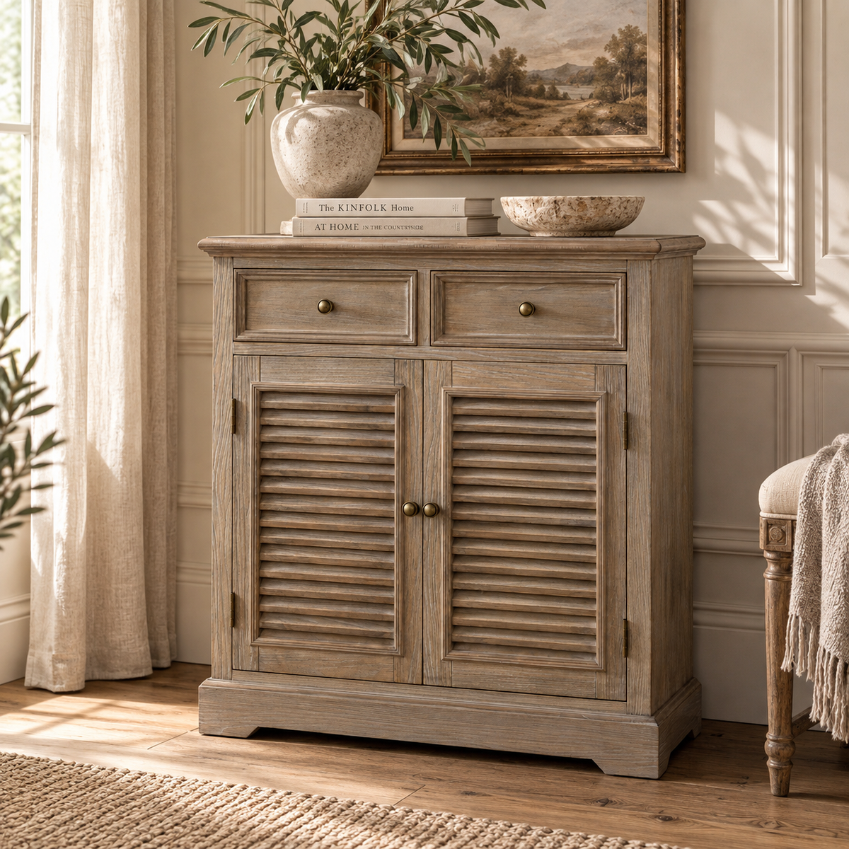 Laurent wood storage chest with 2 drawers and louvred doors in a sunlit living room with artwork and greenery