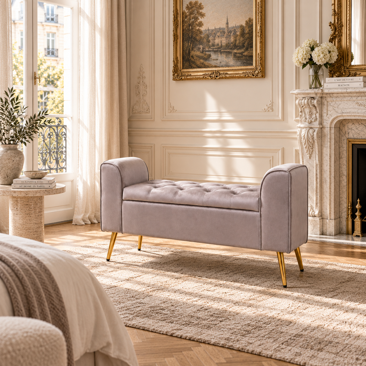 Lucien mink velvet ottoman storage bench with tufted seat and gold legs in a Parisian bedroom with fireplace and rug.