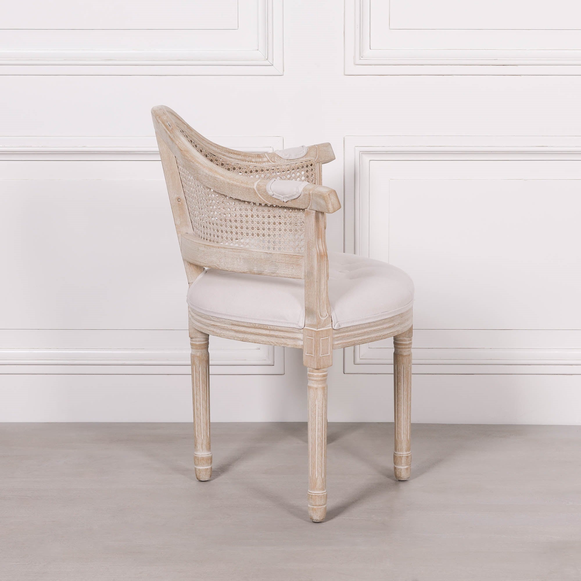Side view of the Lucienne Louis corner chair featuring natural linen upholstery, woven cane backrest and a washed wood frame with classic French styling.