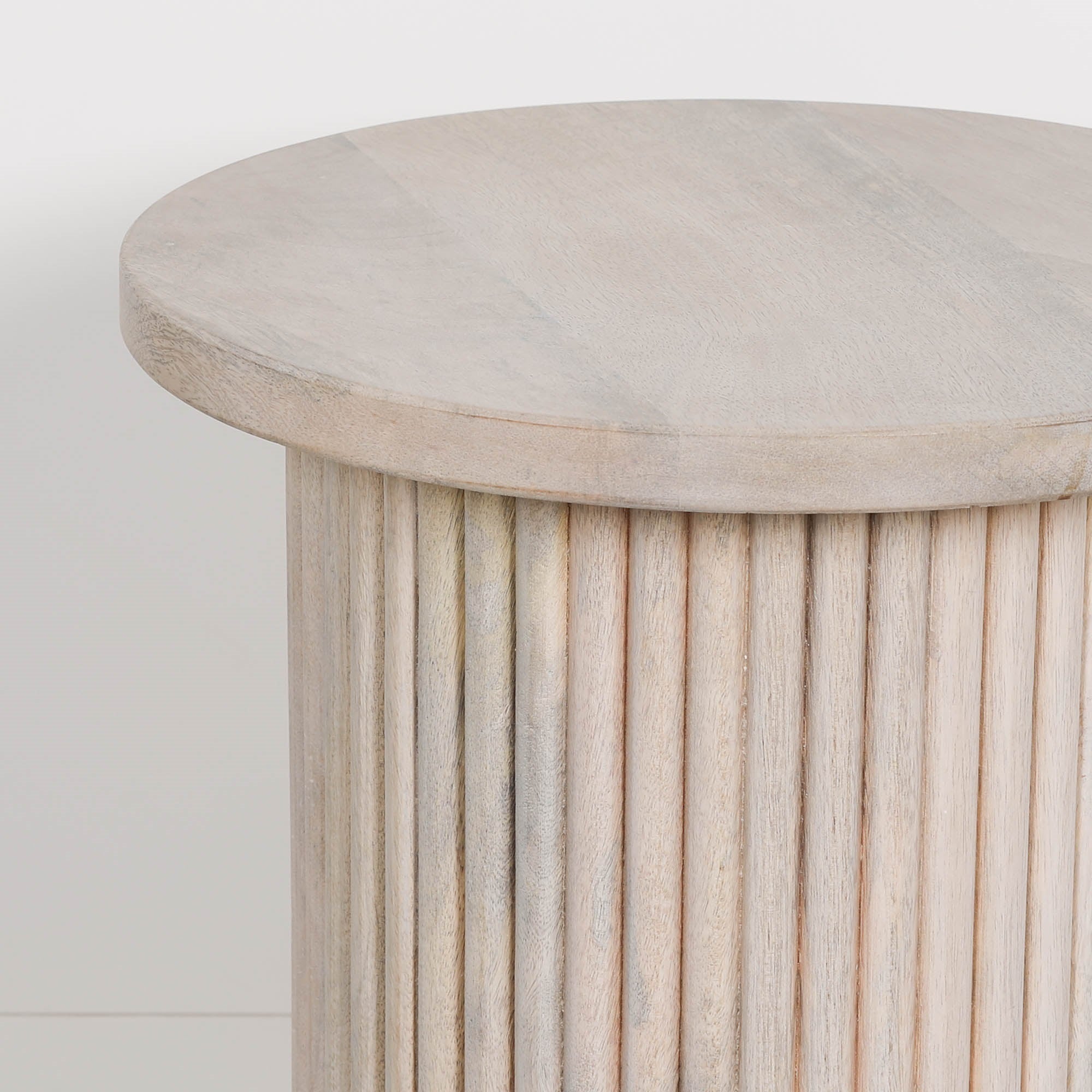 Close-up of the Margaux ribbed round side table in washed mango wood featuring the smooth circular tabletop, natural wood grain and fluted pedestal base, ideal as a modern bedside table or accent table.