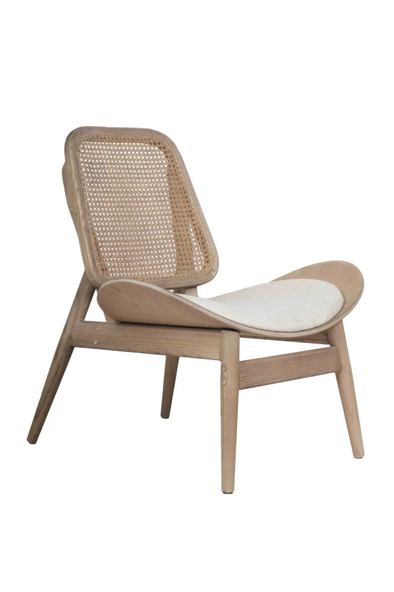 Angled front view of the Vincent Cane Back Lounge Chair highlighting the woven cane backrest, soft beige fabric upholstered seat, curved wooden armrests and washed solid elm wood frame, blending mid-century modern design with coastal and Scandinavian-inspired interiors.