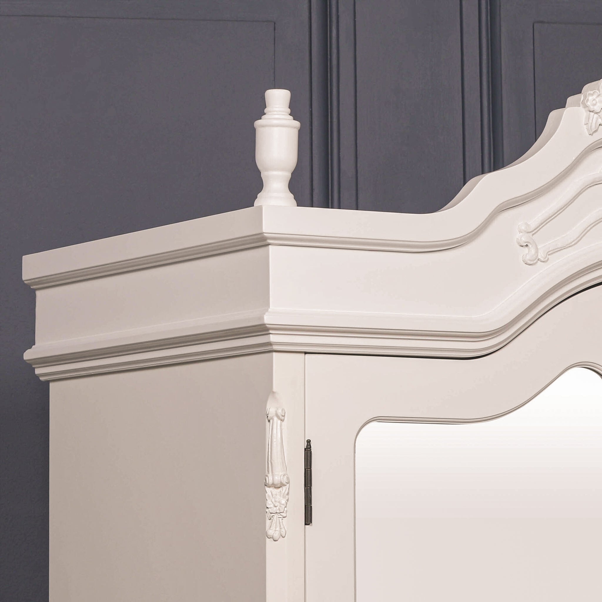 Close-up of French-style armoire wardrobe top detailing with carved crown design