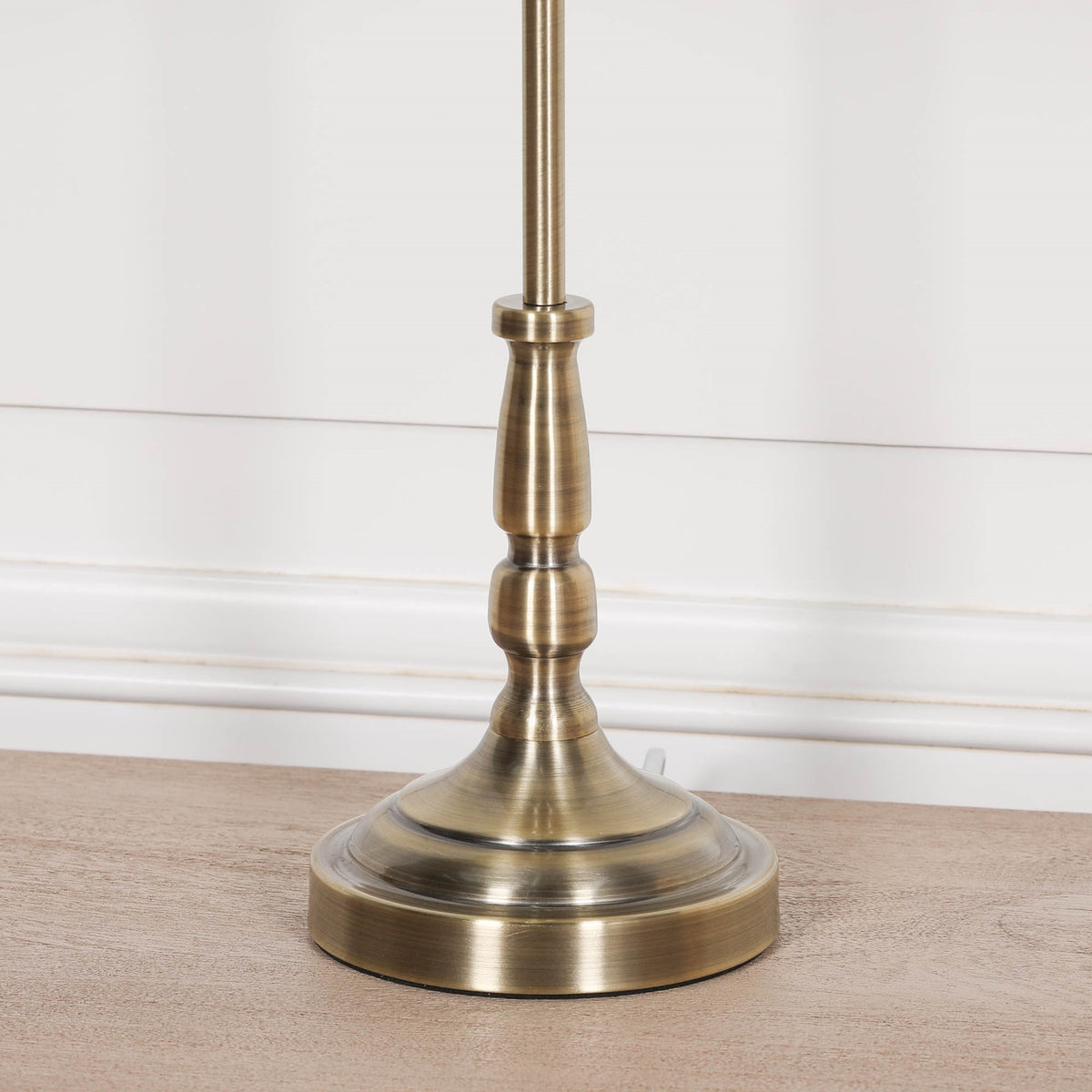 Close-up of the Amélie Classical satin brass candlestick table lamp base showcasing the brushed brass finish and traditional turned detailing on a wooden surface.