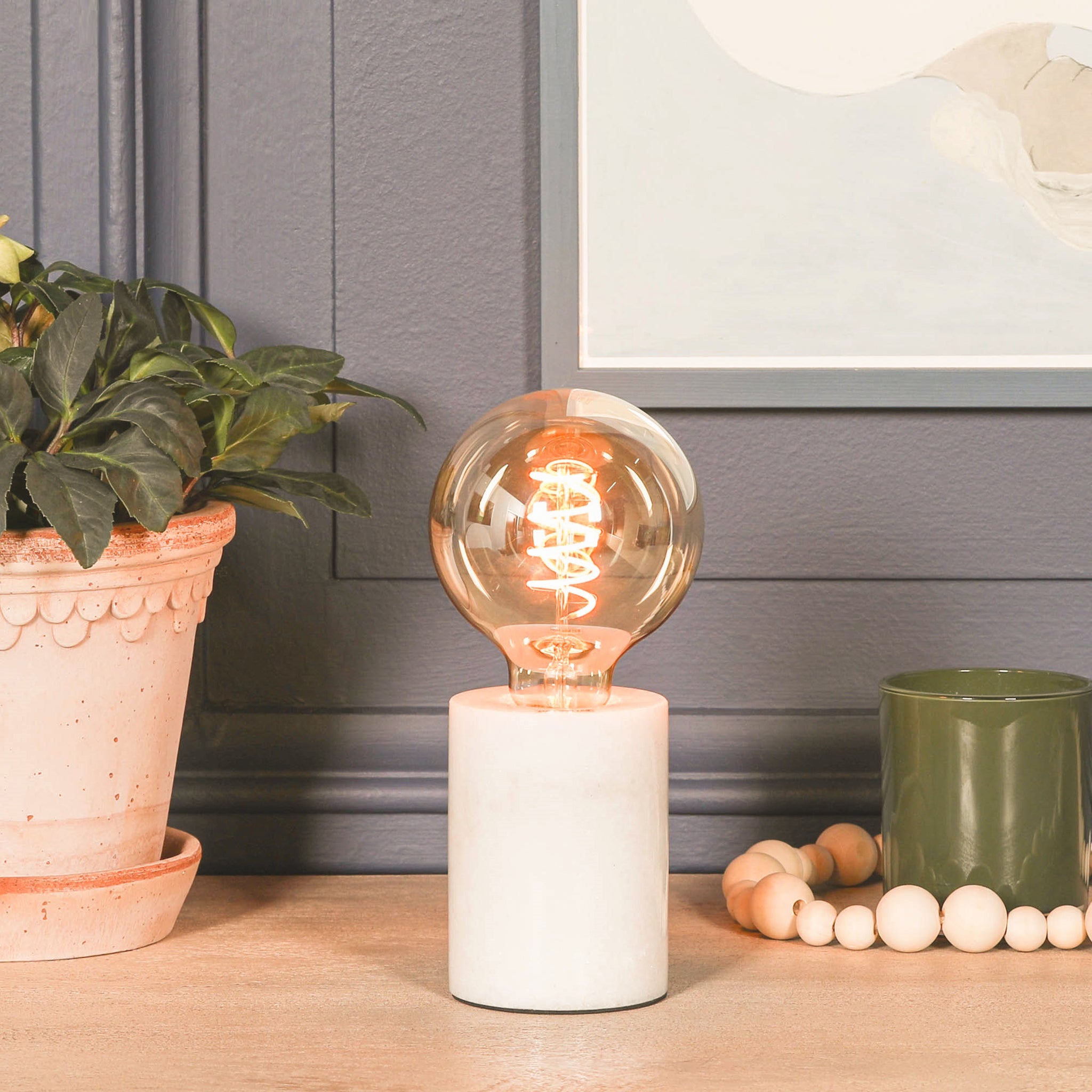 Amélie Industrial White Marble Table Lamp with Braided Cord styled on a wooden side table featuring a solid white marble base, vintage Edison filament bulb and modern industrial lighting for living rooms, bedrooms and home offices.
