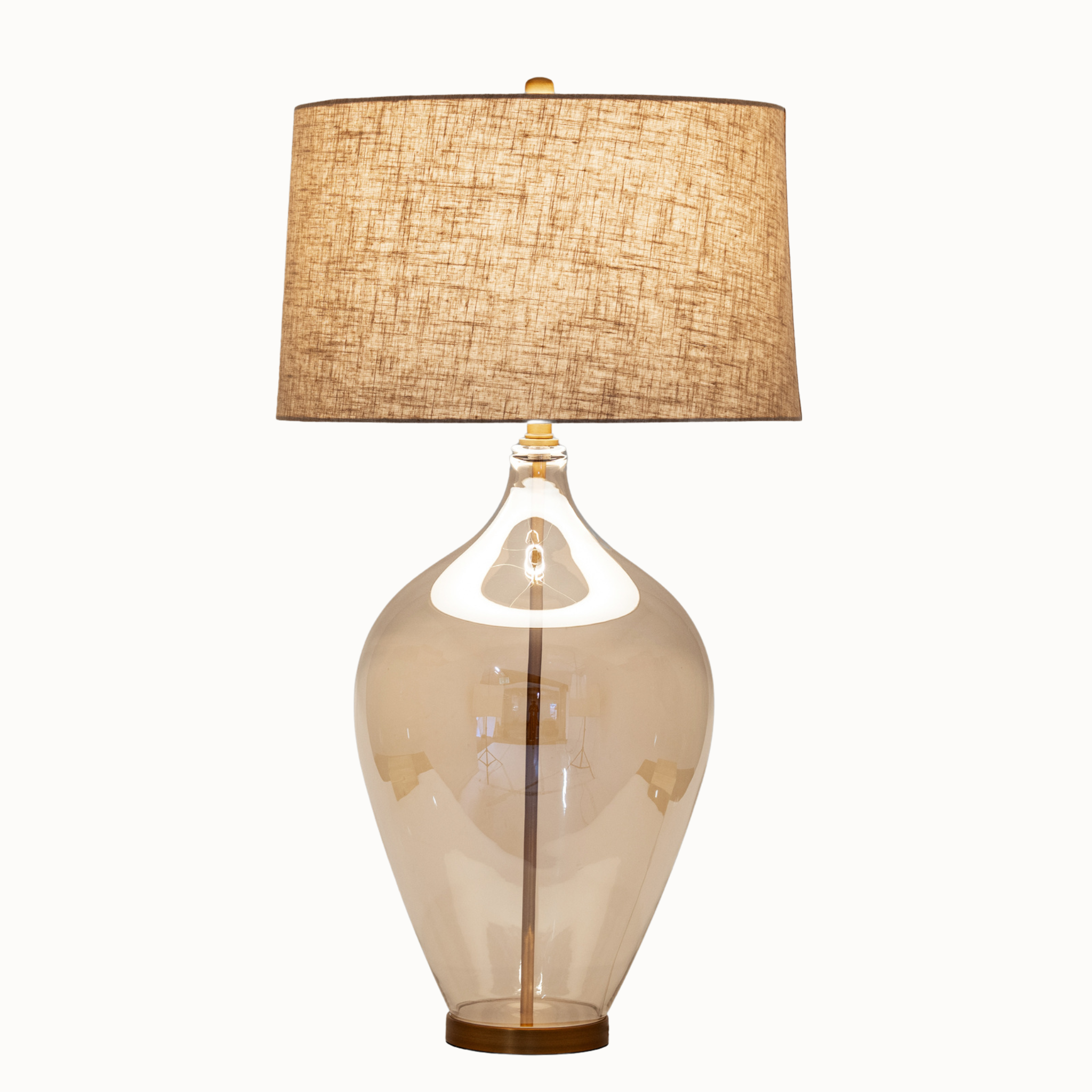 Amélie opaline glass table lamp illuminated with a warm linen shade on a white background.