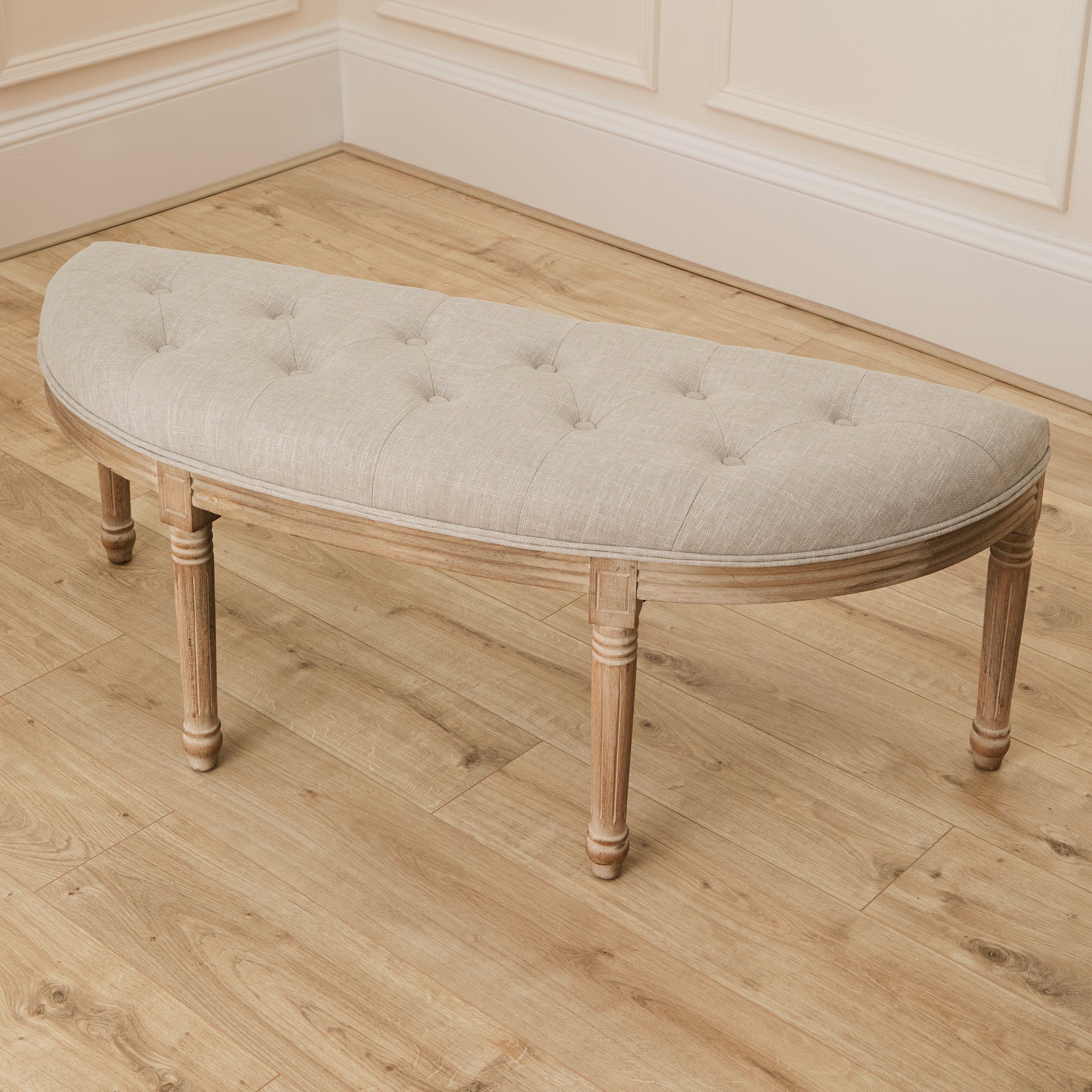 Annette cream tufted wooden bench with natural wood frame against panelled walls and light wood flooring.
