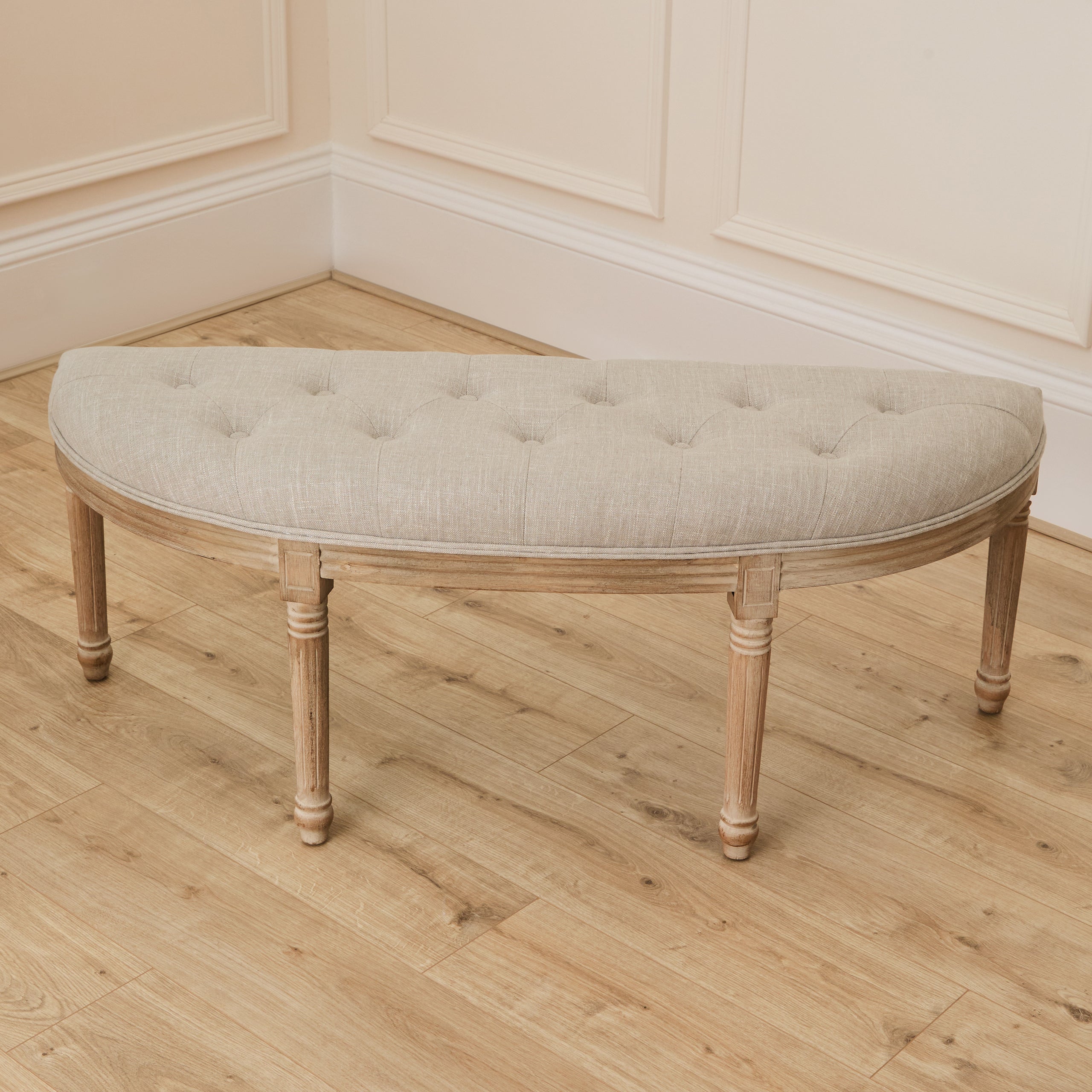 Annette natural wood bench with cream tufted upholstery against white panelled walls and light wood flooring.