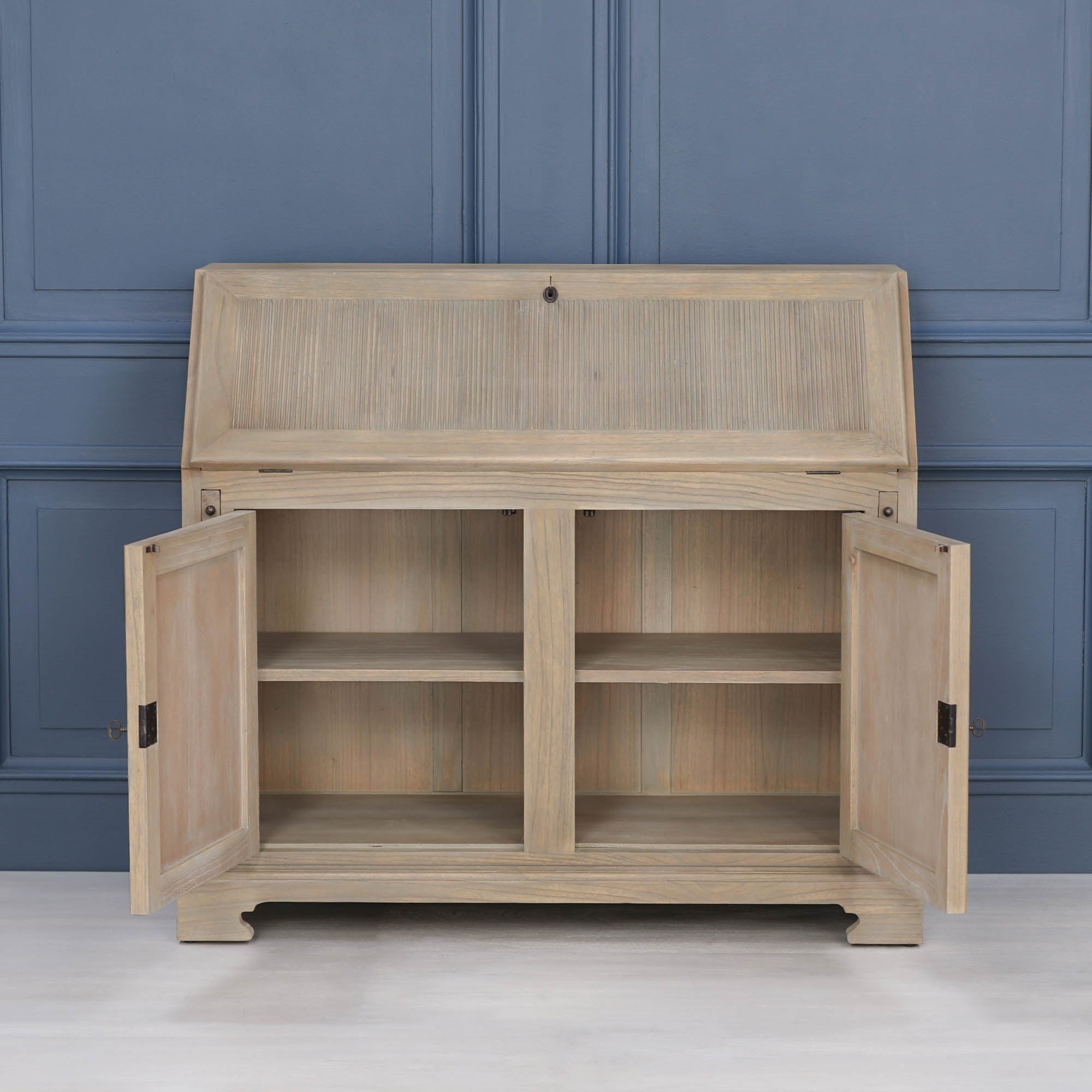 Armand white cedar bureau desk with lower storage doors open, showing shelves against a blue panelled wall.