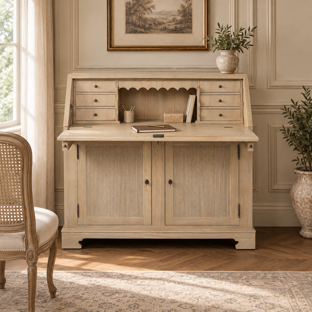 Armand white cedar bureau writing desk with storage in a sunlit Parisian room with cane chair, rug and framed artwork.