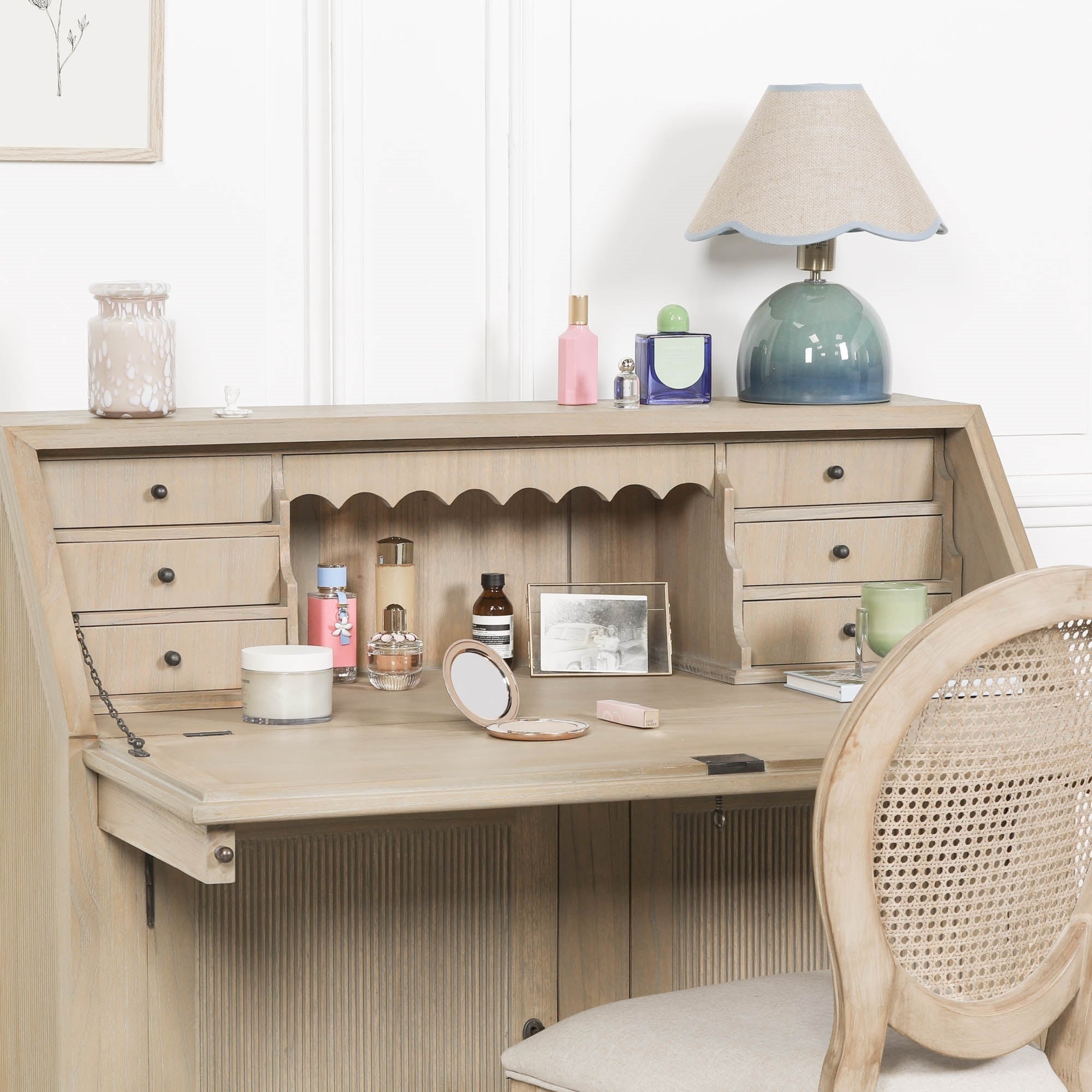 Armand white cedar bureau writing desk styled as a vanity with drawers, storage and chair against a white wall.