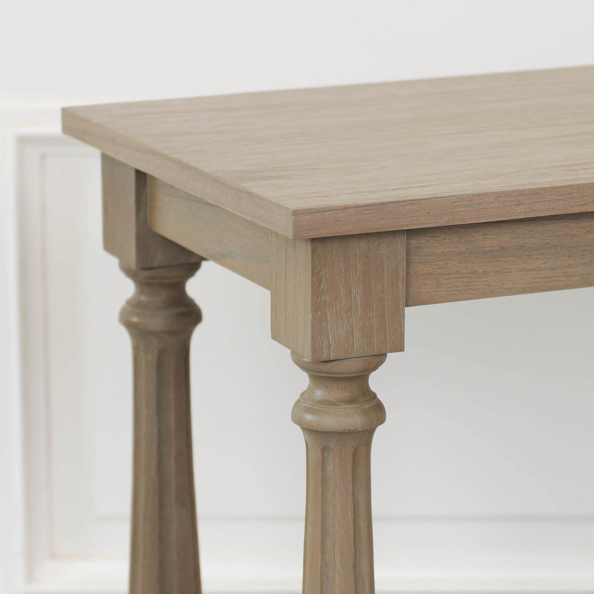 Close-up of Armand white cedar console table showing the wood tabletop, apron and turned leg detailing