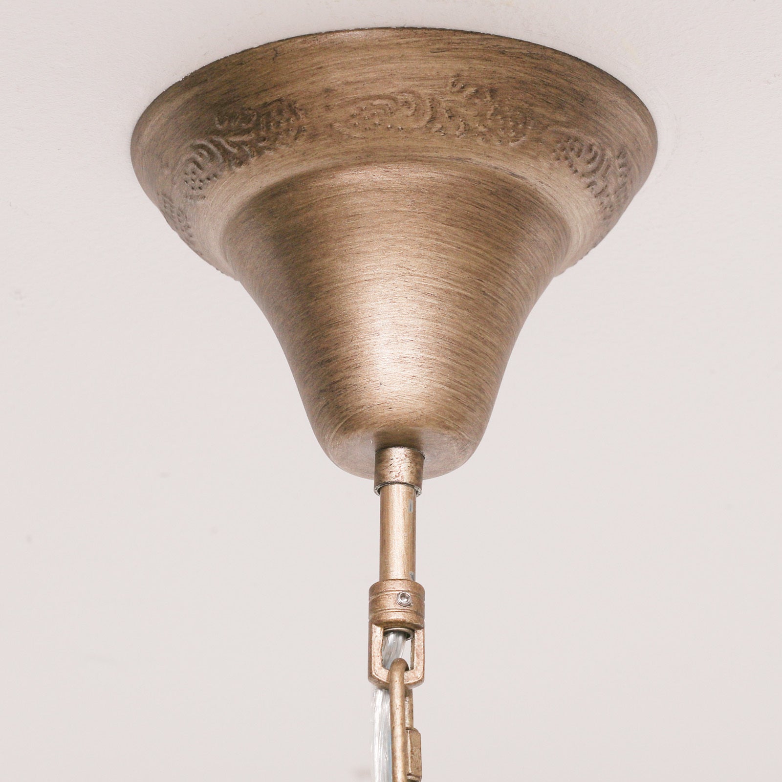 Close-up of Aubert chandelier gold ceiling rose and chain against a plain white ceiling.