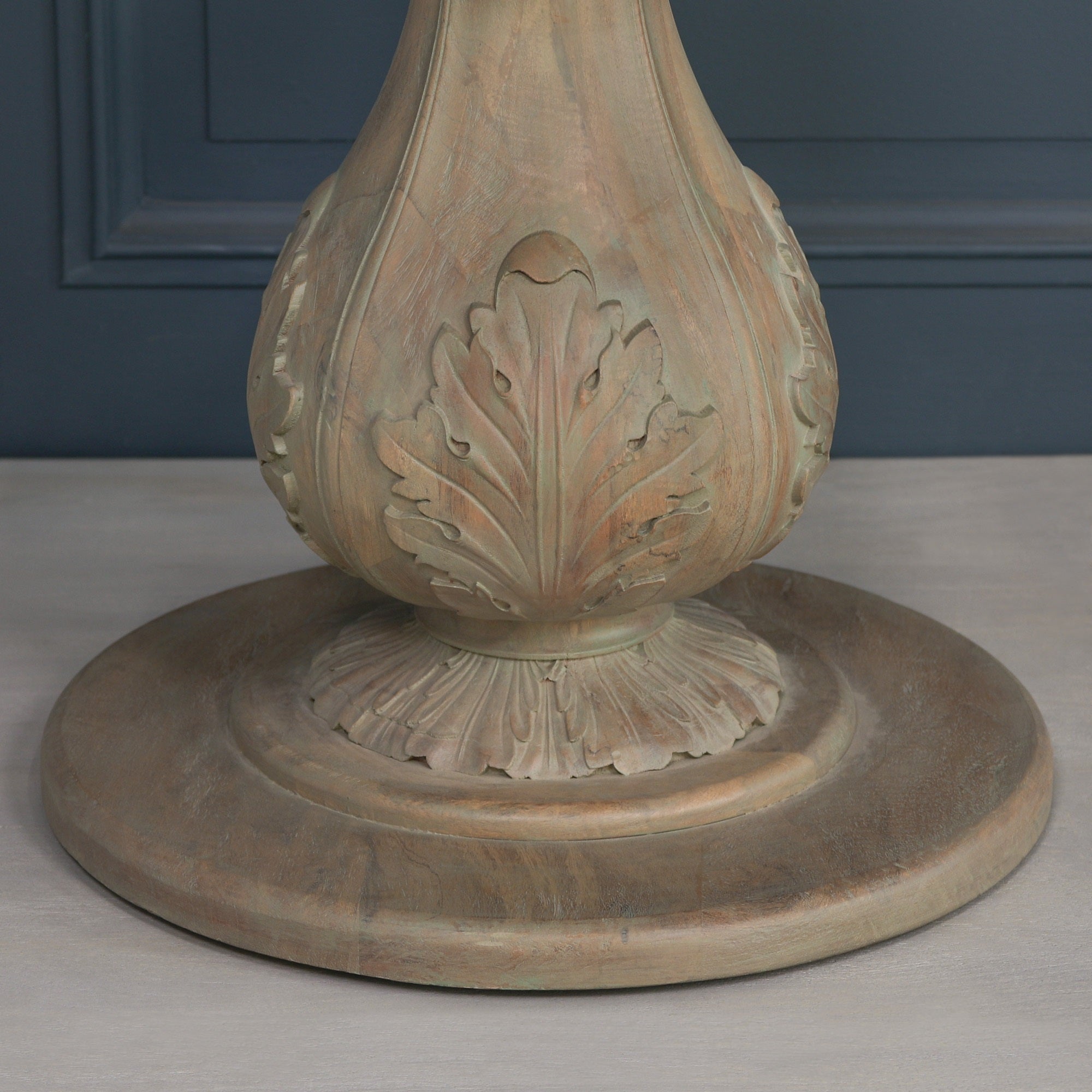 Close-up of the carved acorn pedestal base on the Auguste Round Acorn Pedestal Dining Table in Rustic Washed Hardwood, showcasing detailed botanical leaf carvings, solid hardwood craftsmanship and sculptural French country inspired design.