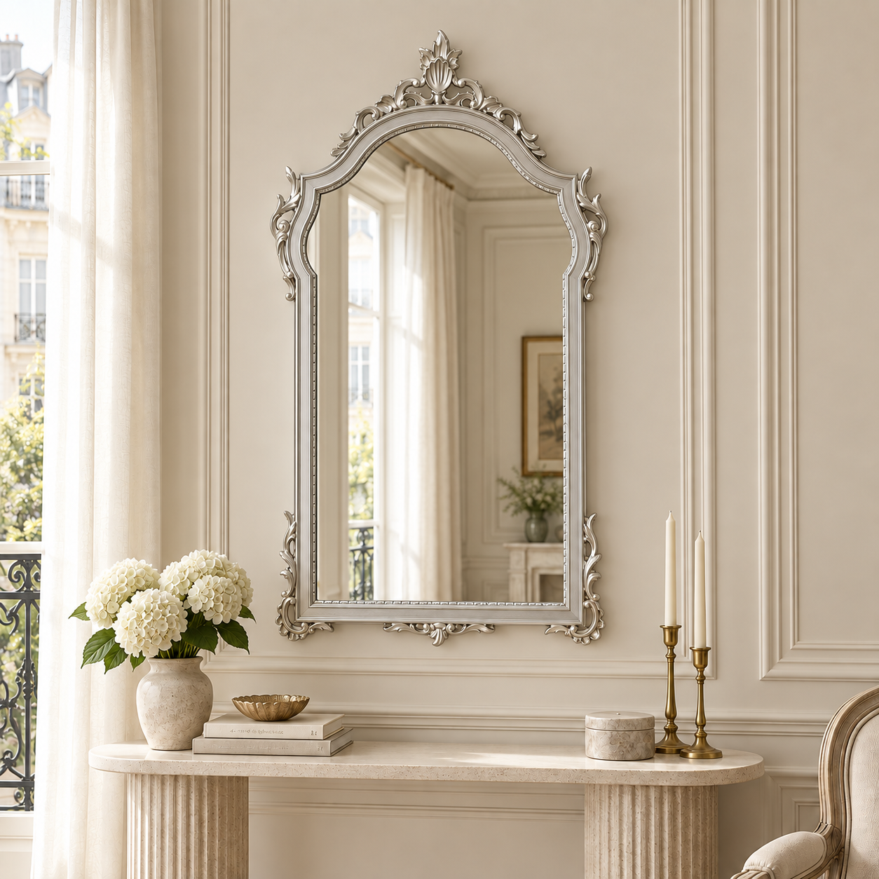 Aurelia silver framed wall mirror above a console table in a bright Parisian-style room with cream panelled walls.
