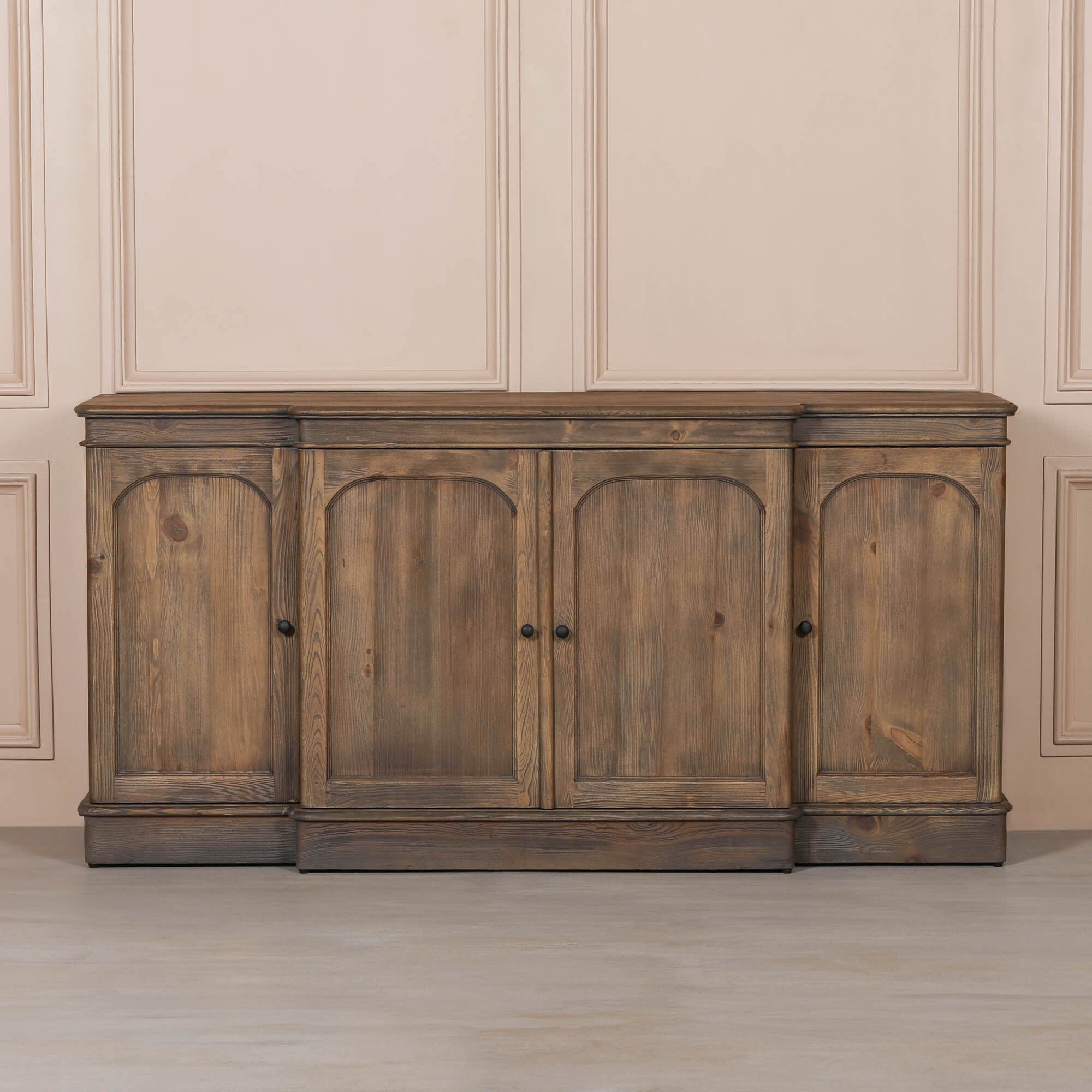 Aveline 190cm rustic pine wood 4 door sideboard against a neutral panelled wall with pale wood flooring.