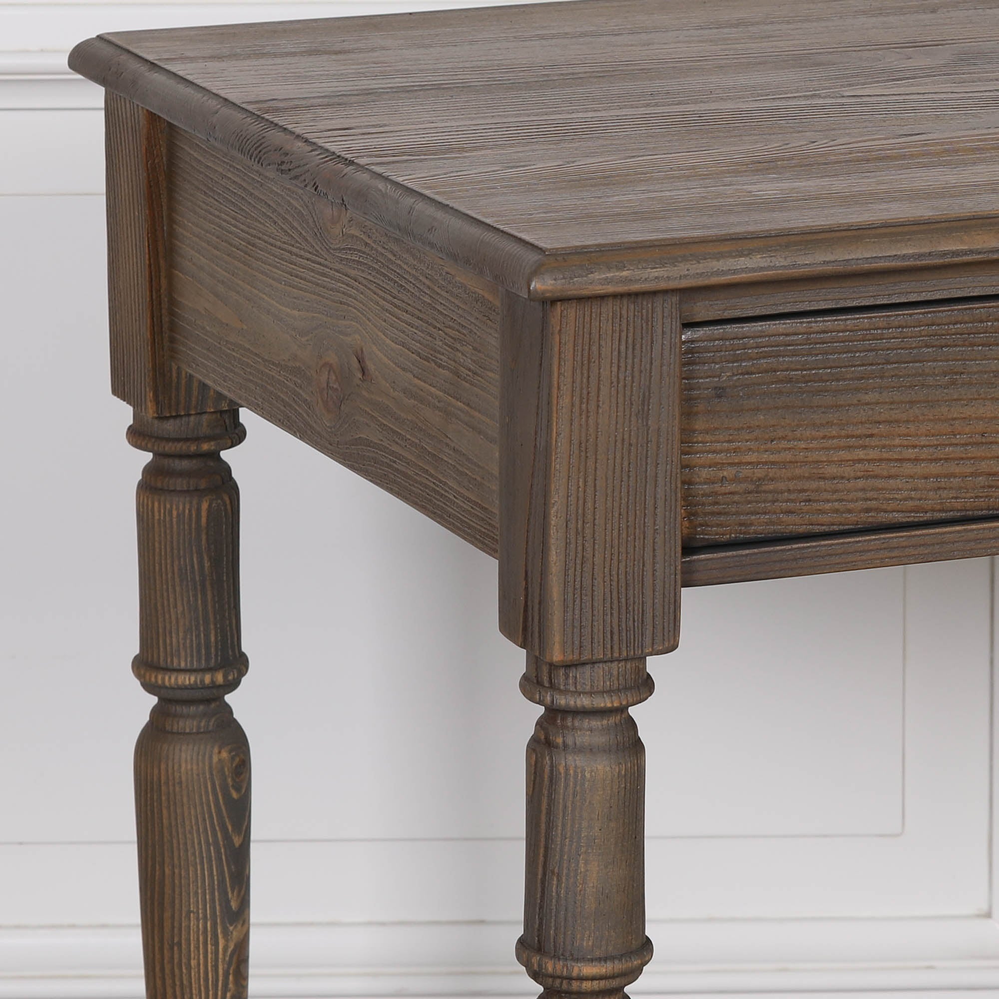Aveline pine wood writing desk close-up showing wood grain, tabletop and turned legs against a white panelled wall