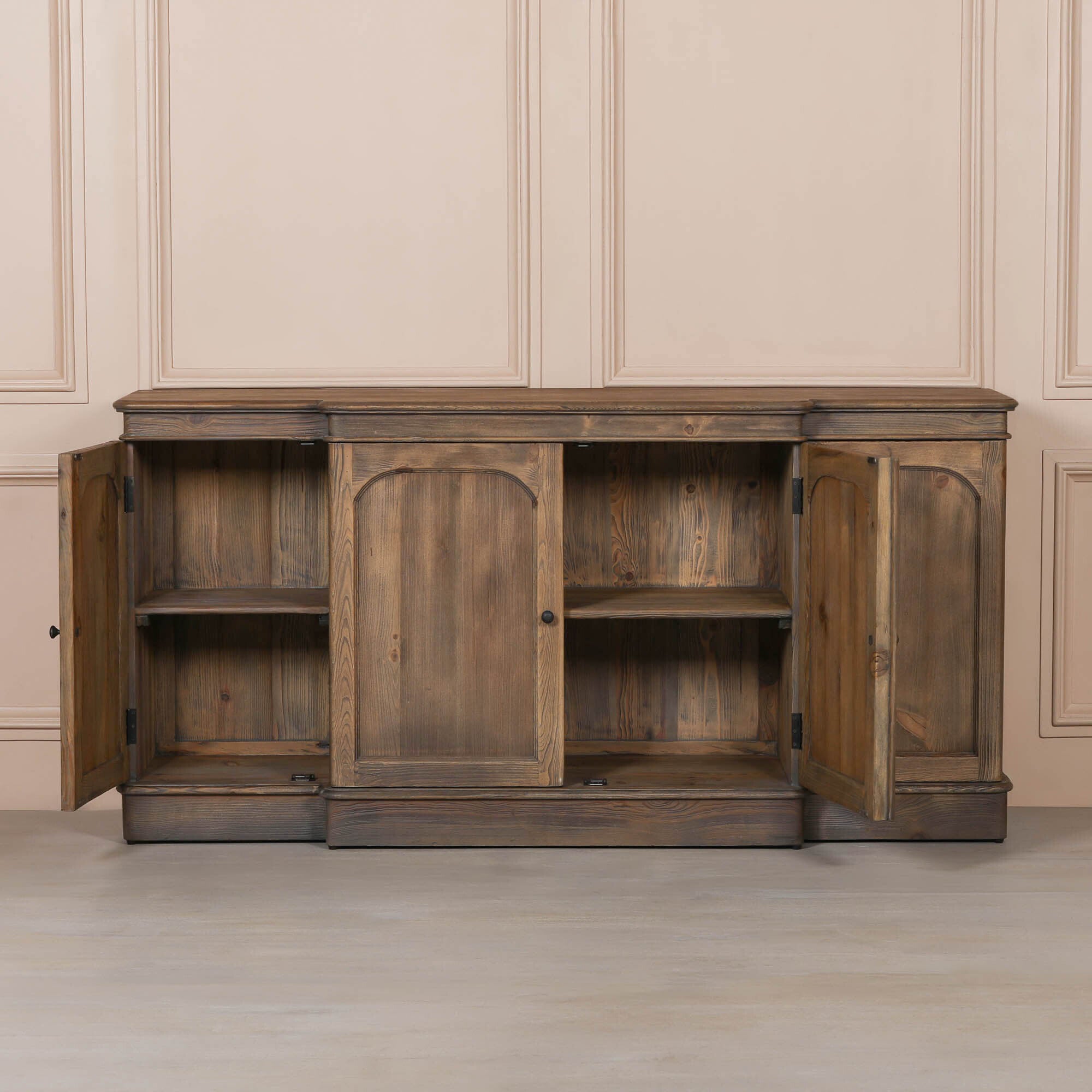 Aveline rustic pine 4 door sideboard open to show internal shelving against a neutral panelled wall.