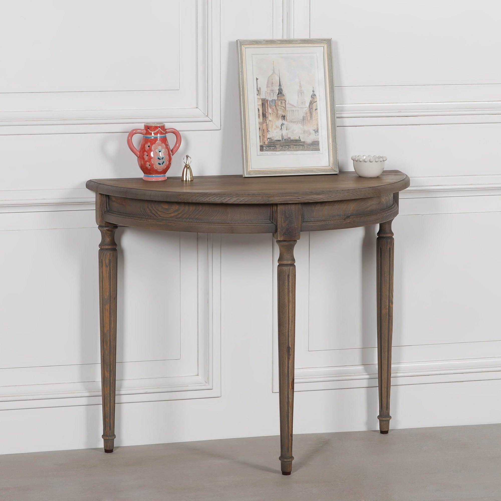 Aveline rustic pine demi-lune hallway table with curved top and turned legs, styled with framed art and accessories.