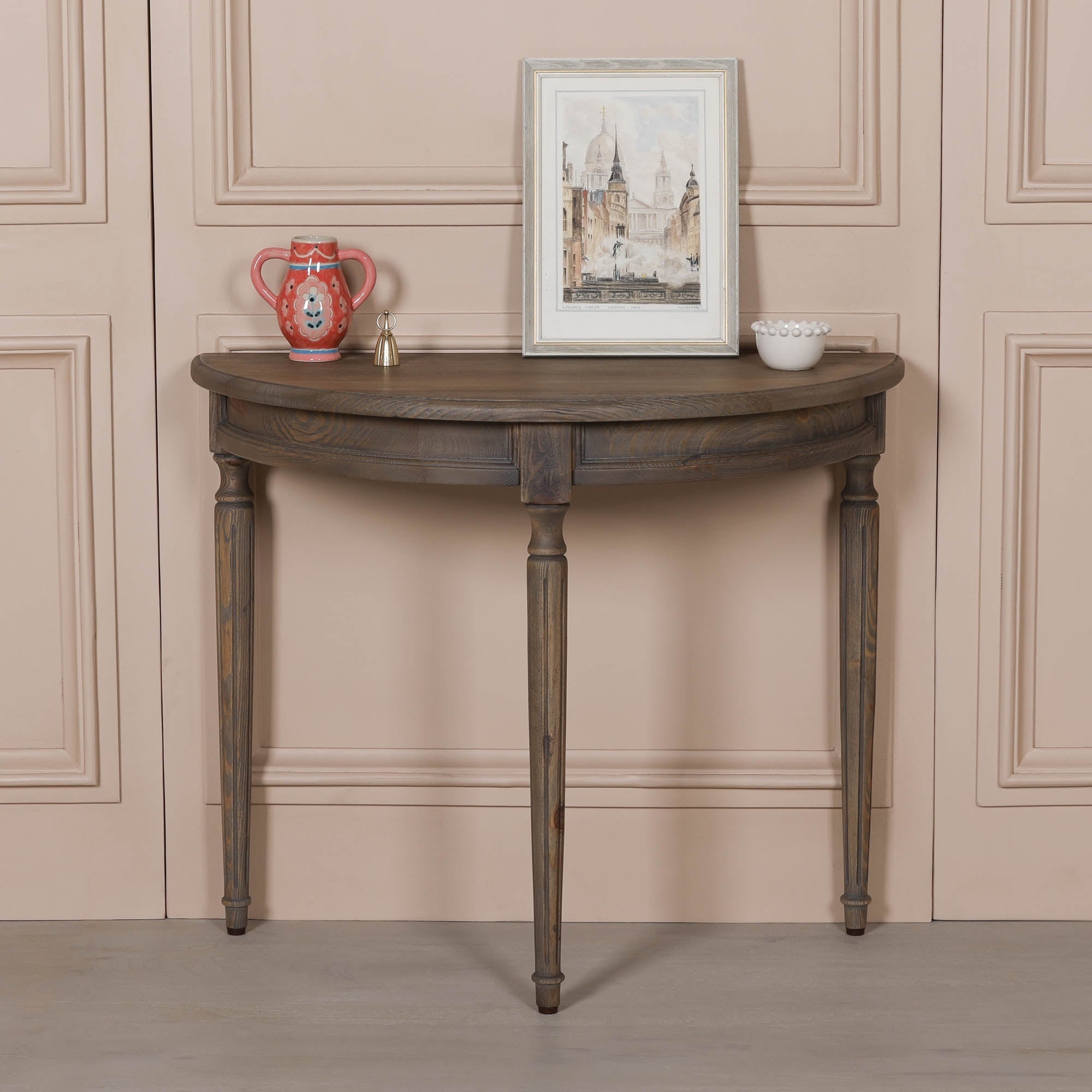 Aveline rustic pine wood demi-lune console table with curved top and turned legs, styled against a panelled wall.
