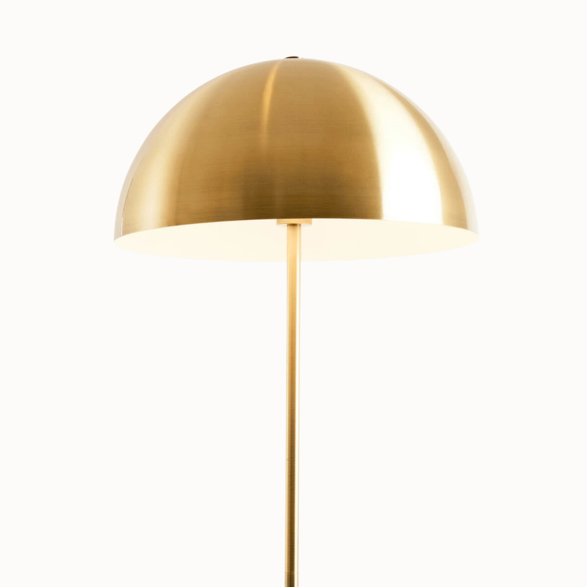 Close-up of Benoît brushed brass dome shade illuminated against a plain white background.