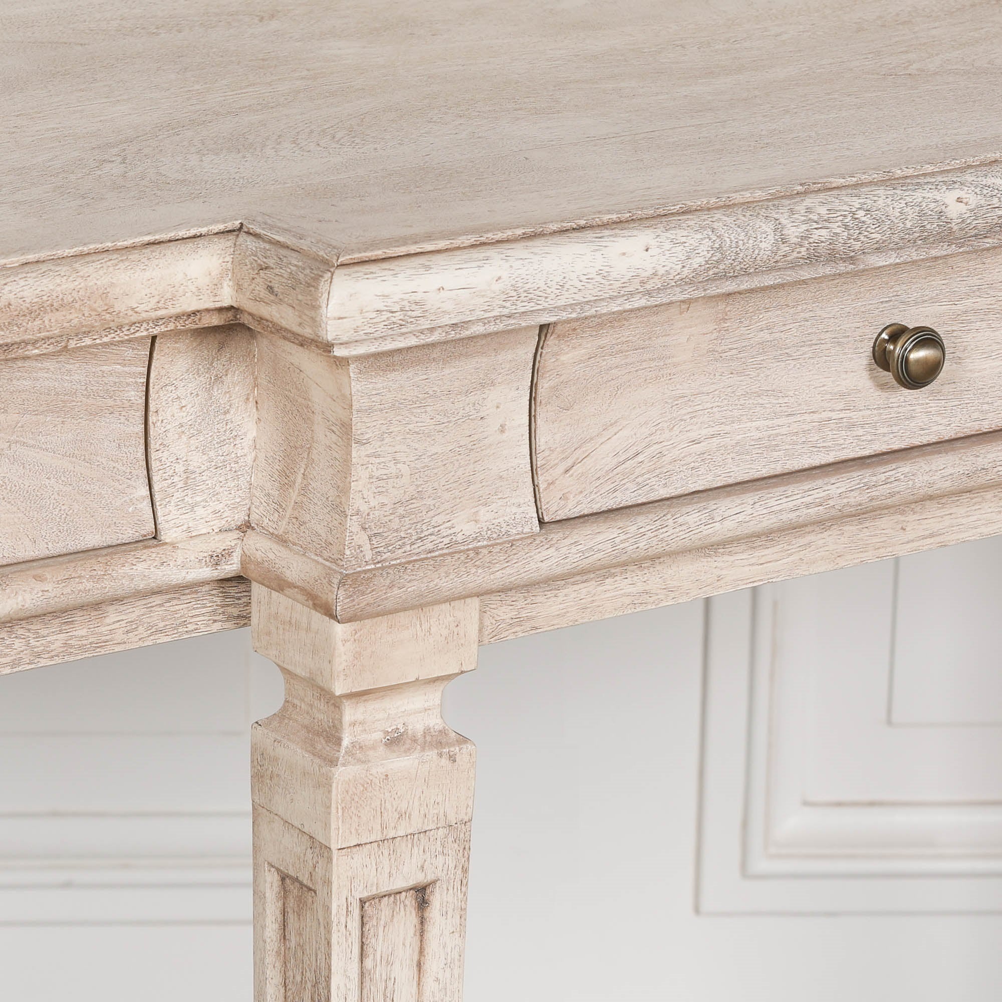 Camille acacia wood breakfront console table drawer and brass knob detail against a white panelled wall