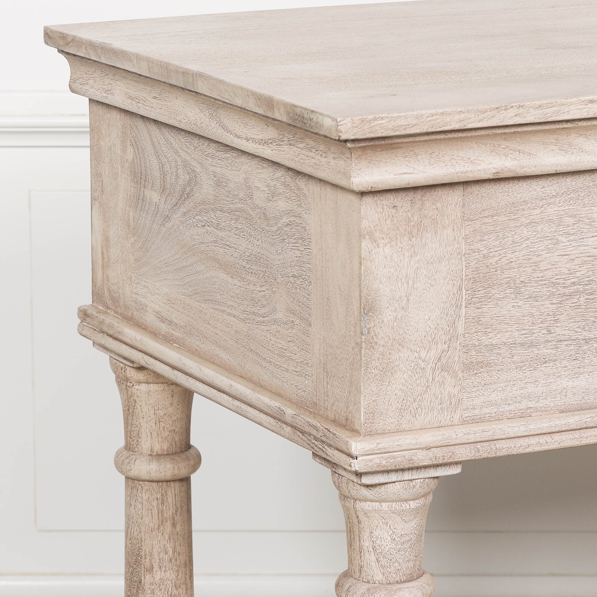 Close-up of Camille acacia wood console table top and side grain against a white panelled wall