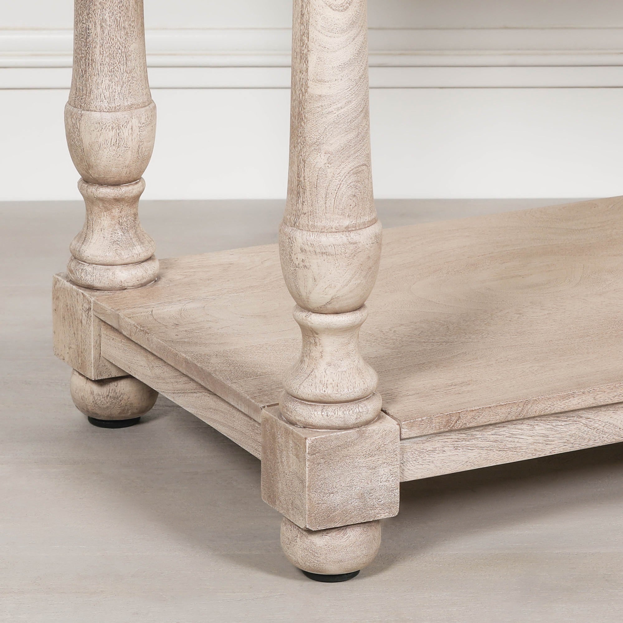 Camille acacia console table detail showing turned legs, rounded feet and lower shelf against a white panelled wall