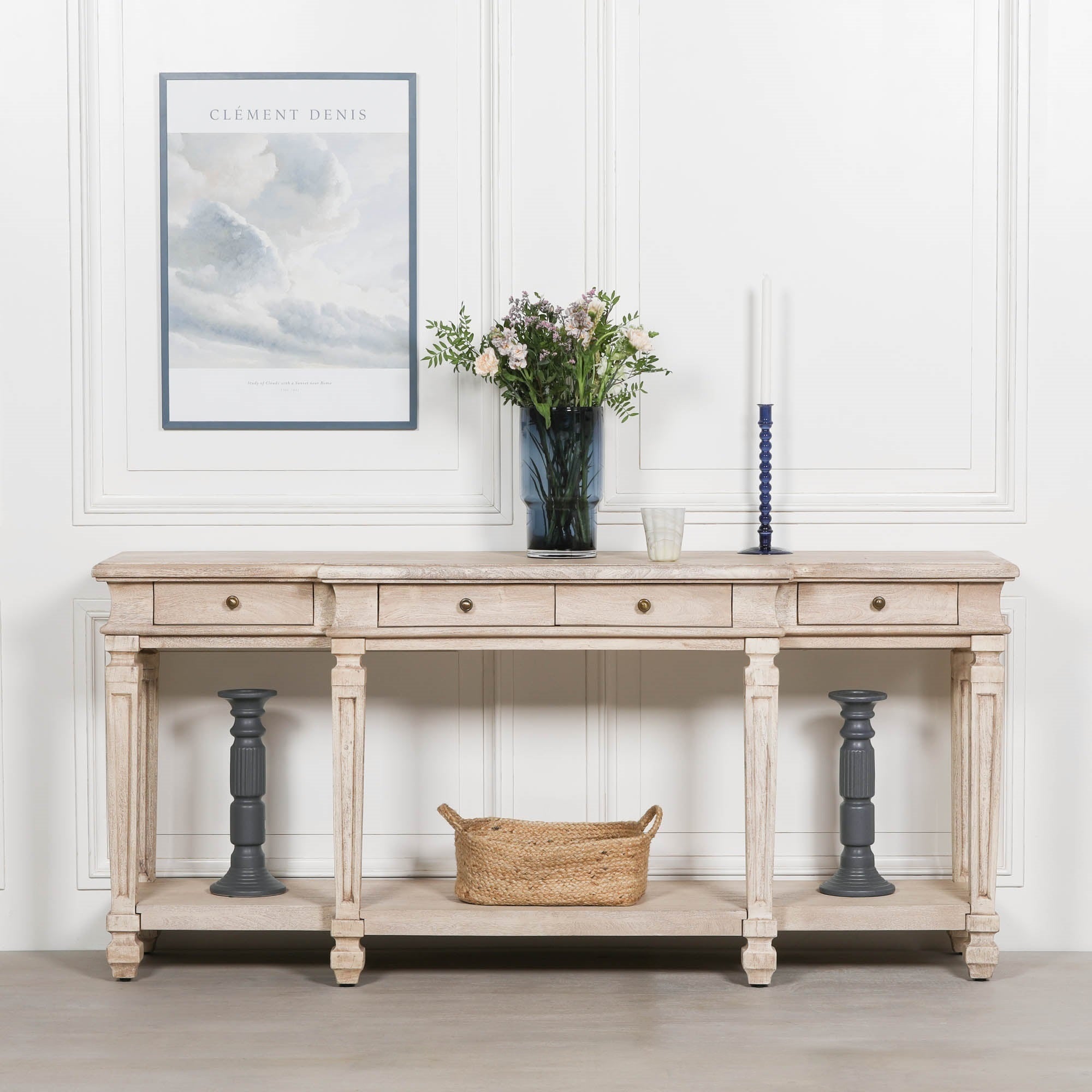 Camille acacia wood 4 drawer breakfront console table styled with flowers against a white panelled wall