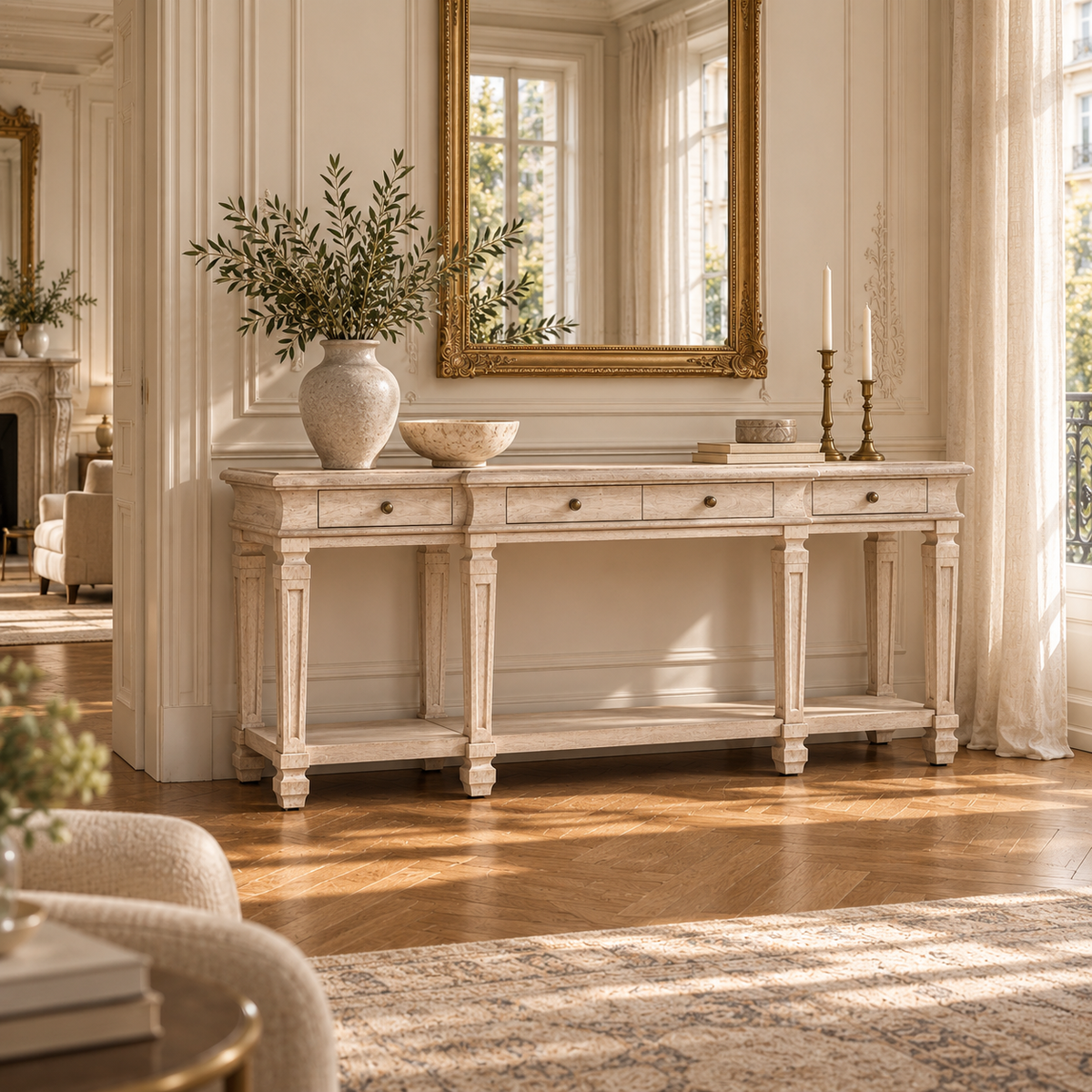 Camille acacia wood 4 drawer console table with lower shelf in a bright room with gold mirror, tall windows and wood floor.