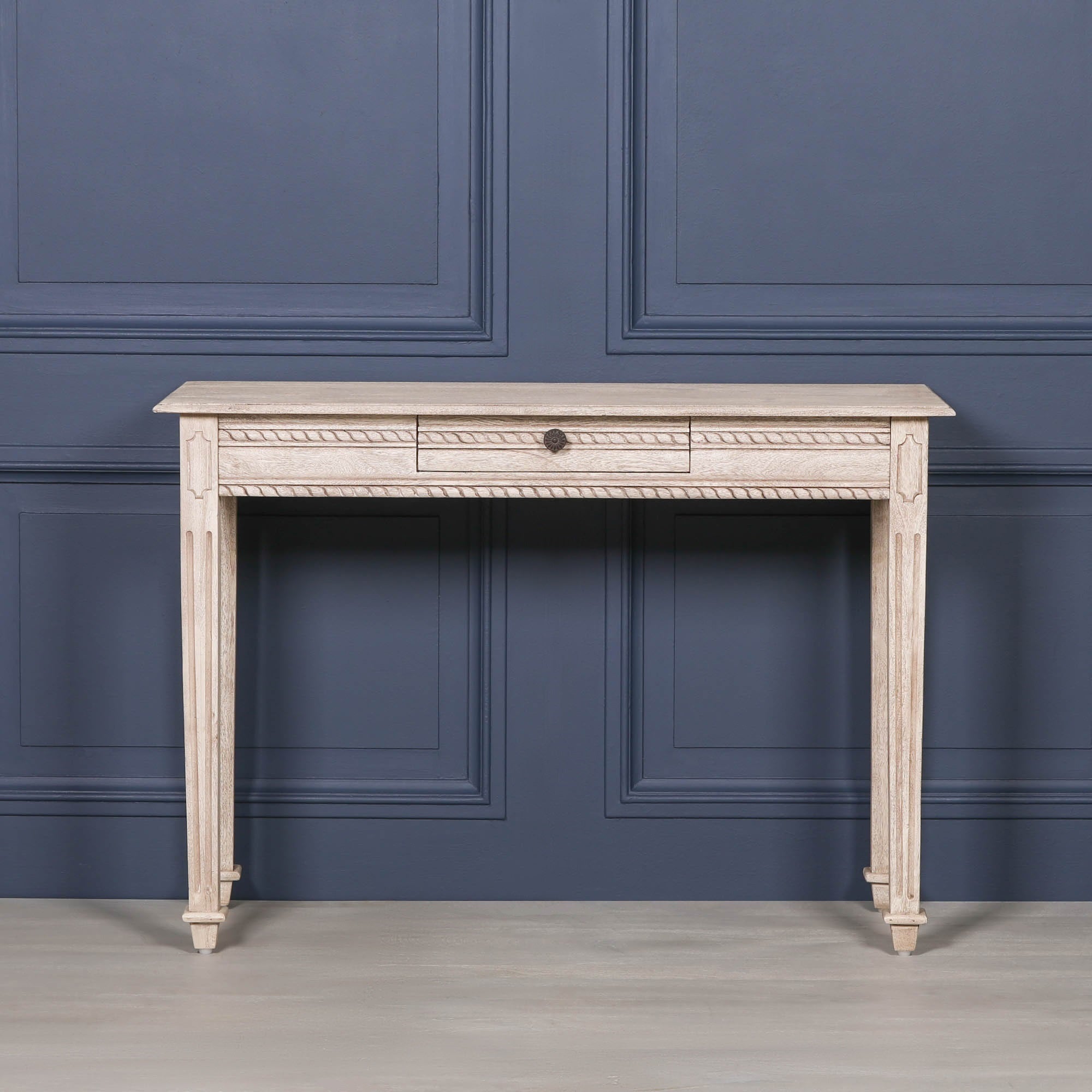 Camille acacia wood dressing table with central drawer and carved trim against a dark blue panelled wall