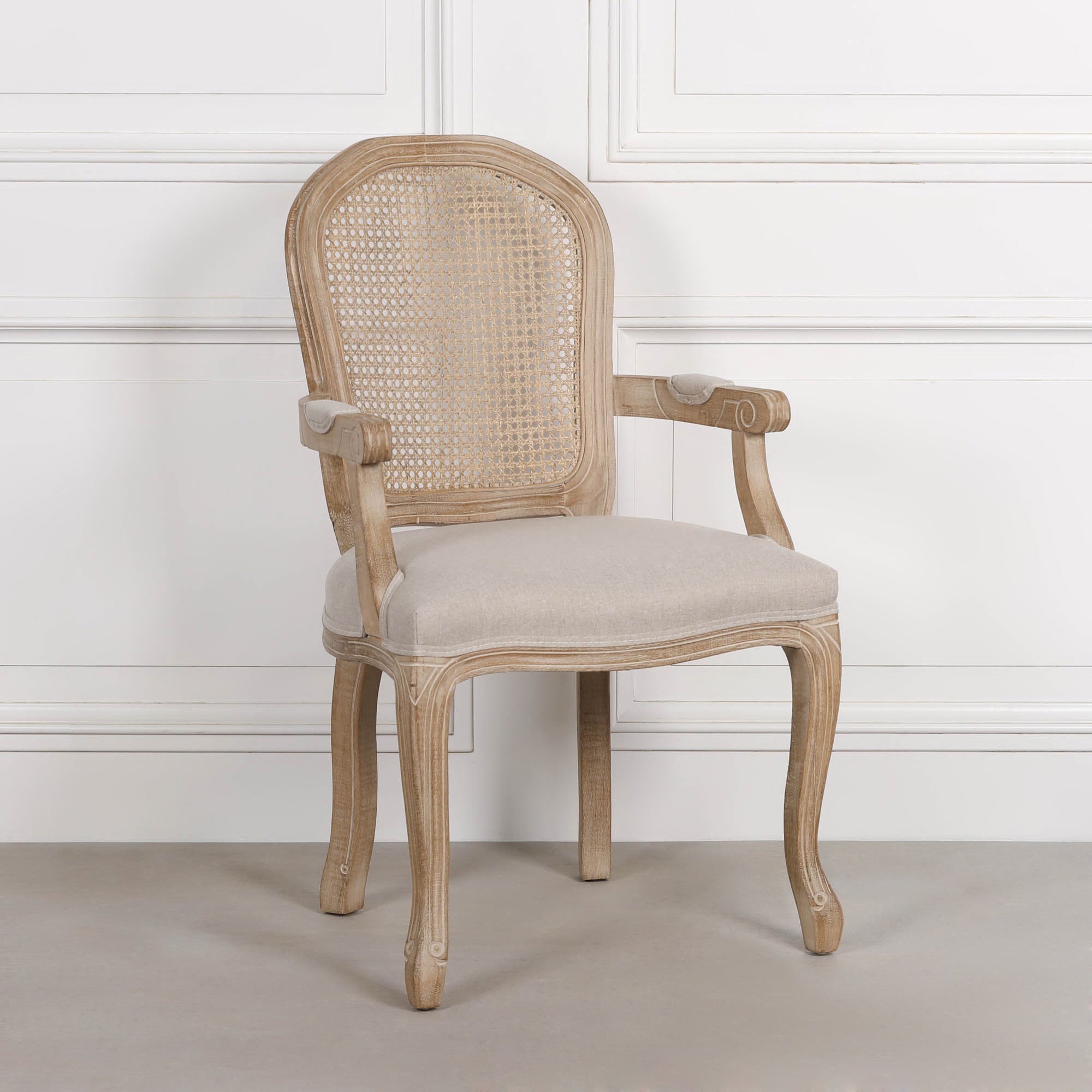 Camille birch wood cane back dining armchair with linen upholstered seat against a white panelled wall