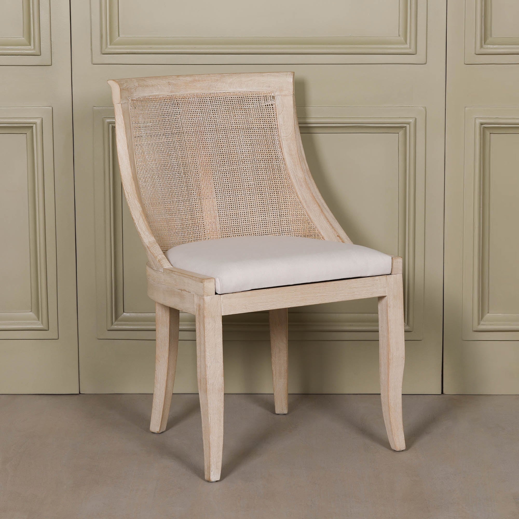 Front angled view of the Camille Cane Back Dining Chair featuring a handwoven natural cane backrest, beige linen upholstered seat and washed birch wood frame, showcasing a timeless French country dining chair for elegant dining rooms and luxury interiors.