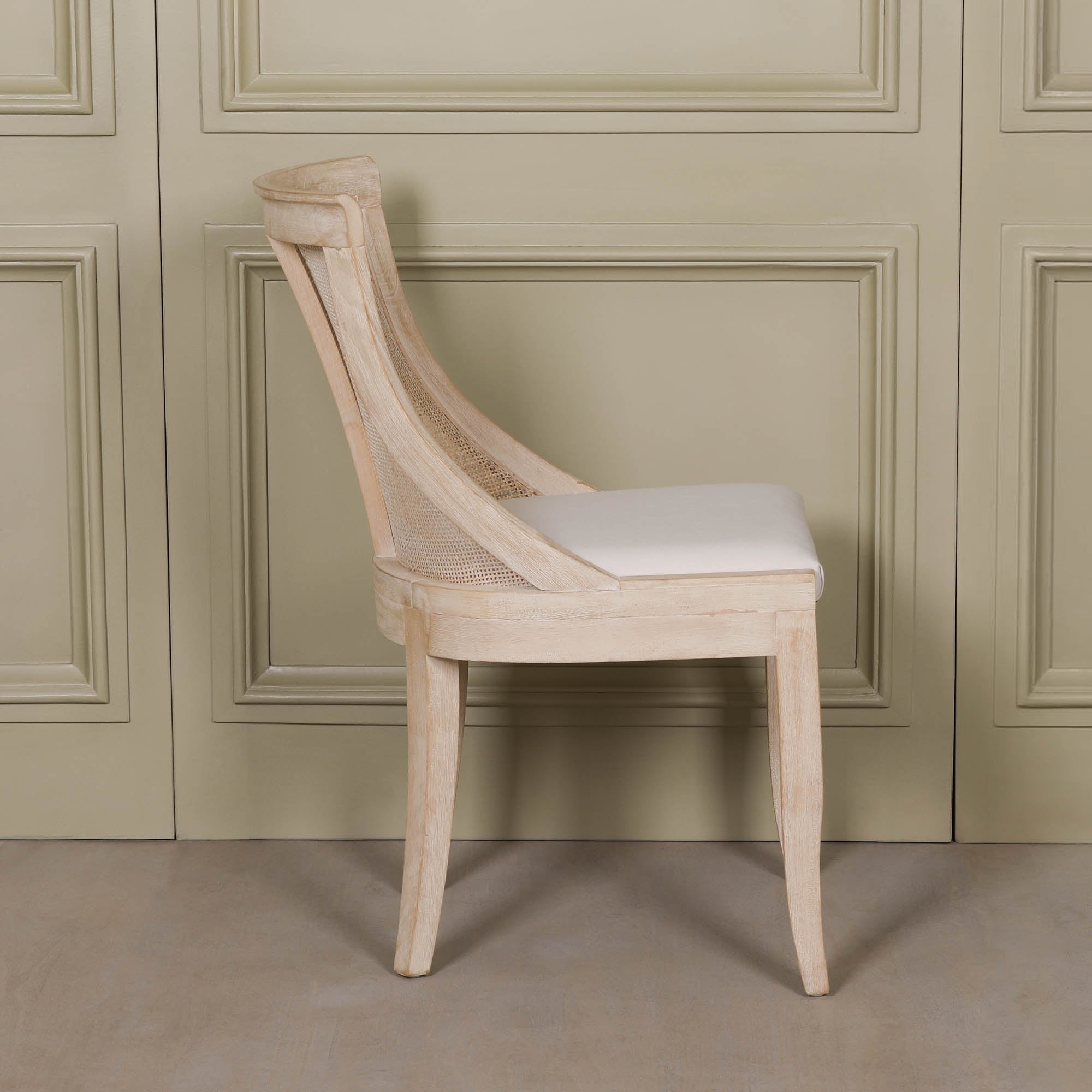 Side profile of the Camille Cane Back Dining Chair highlighting the gently curved silhouette, woven cane back, beige linen upholstered seat and solid washed birch wood frame for timeless dining room seating.