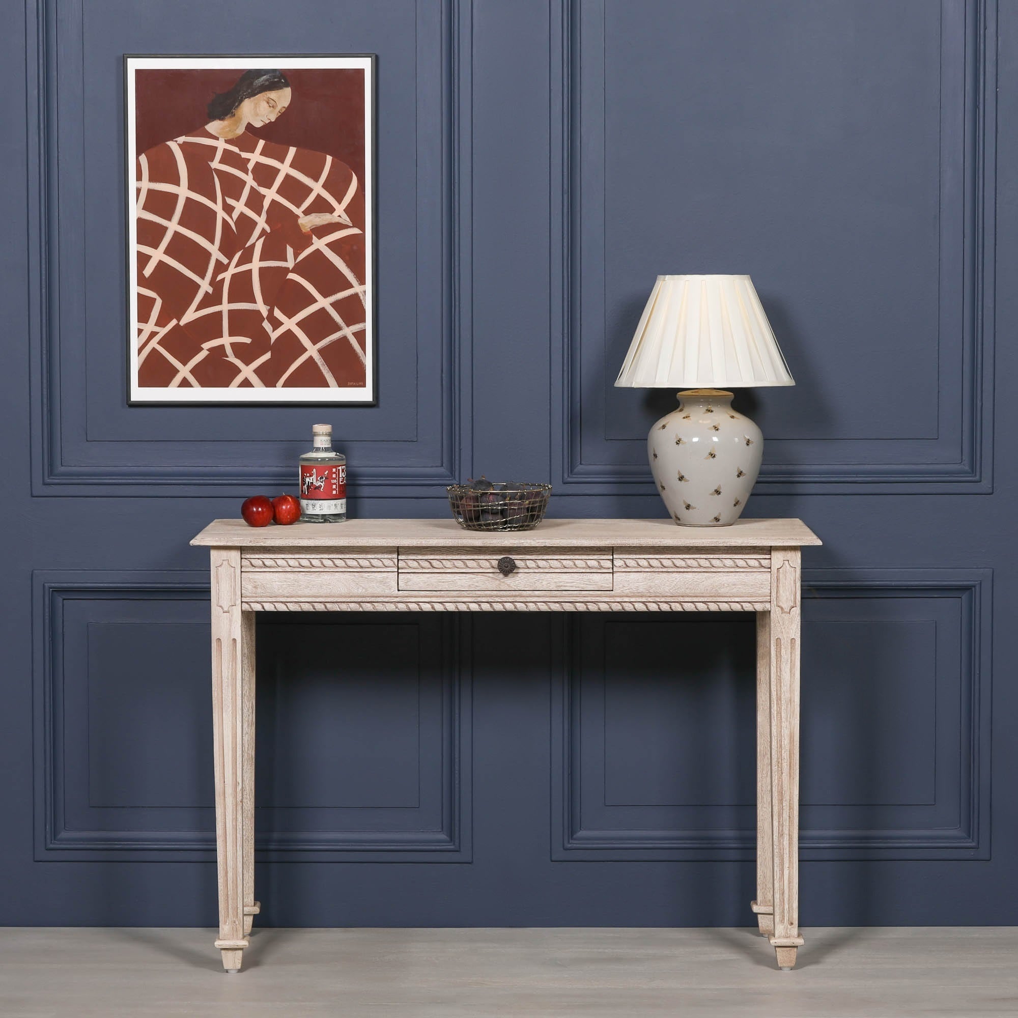 Camille carved acacia wood dressing table with drawer, styled with lamp and artwork against a dark blue panelled wall