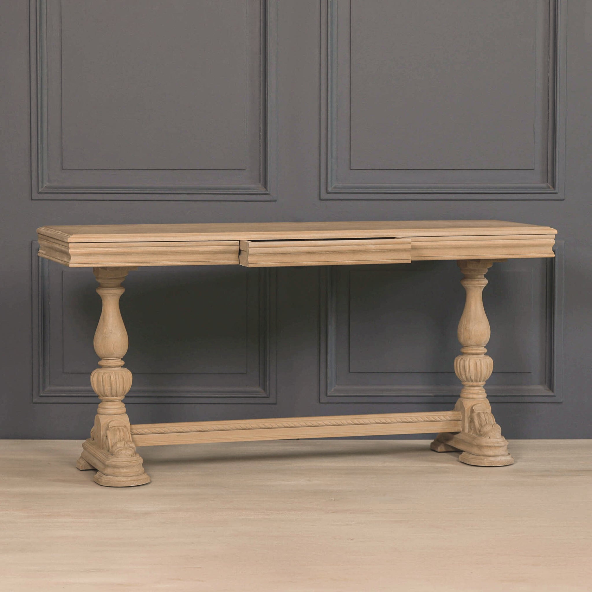 Camille Carved White Cedar Wood Console Table with Drawer displayed against a charcoal grey panelled wall, highlighting the natural white cedar wood finish, carved detailing and traditional farmhouse console table styling.
