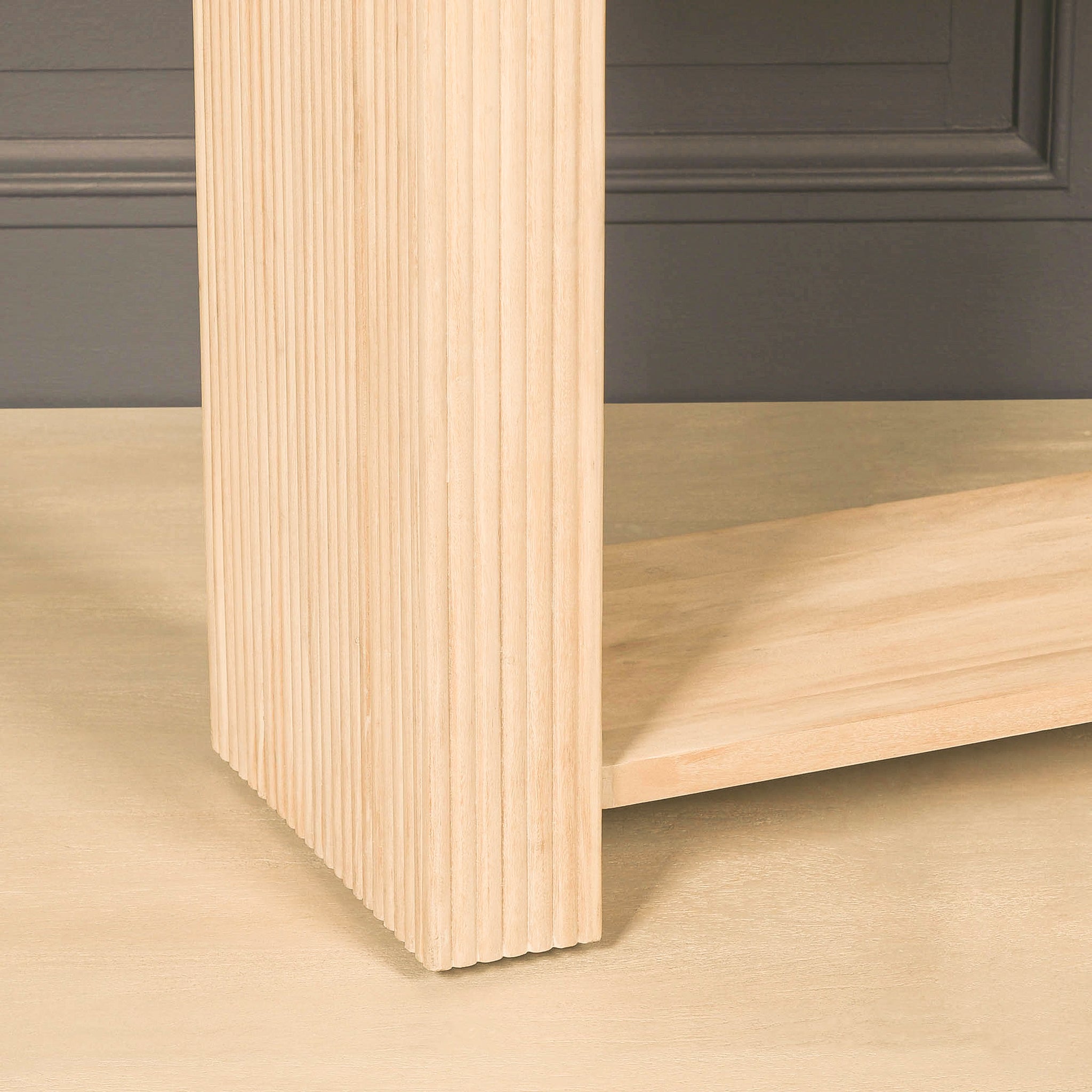 Detailed close-up of the Camille console table showing the fluted acacia wood leg, textured vertical grooves, natural grain and lower storage shelf in a bleached washed finish.