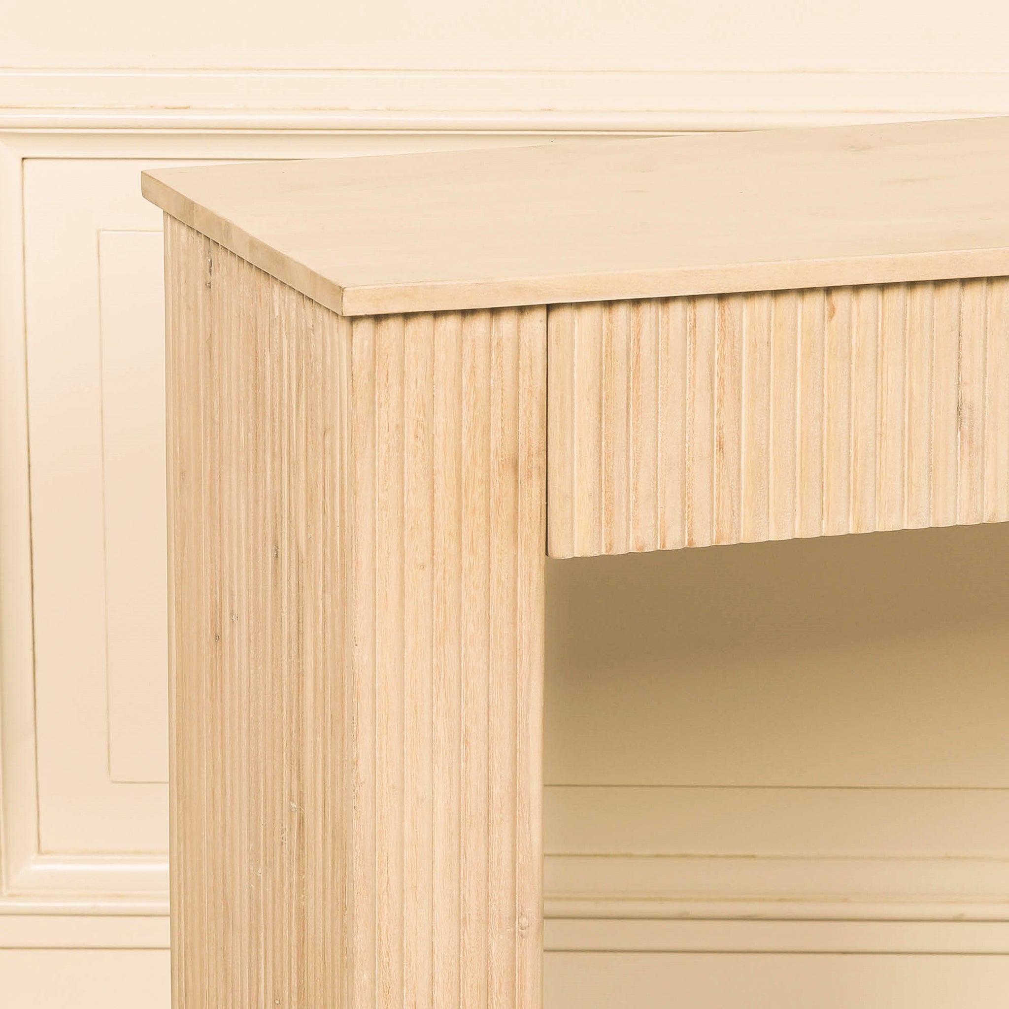 Close-up of the Camille acacia wood console table highlighting its smooth rectangular top, vertically fluted drawer front and matching textured leg in a bleached washed finish.