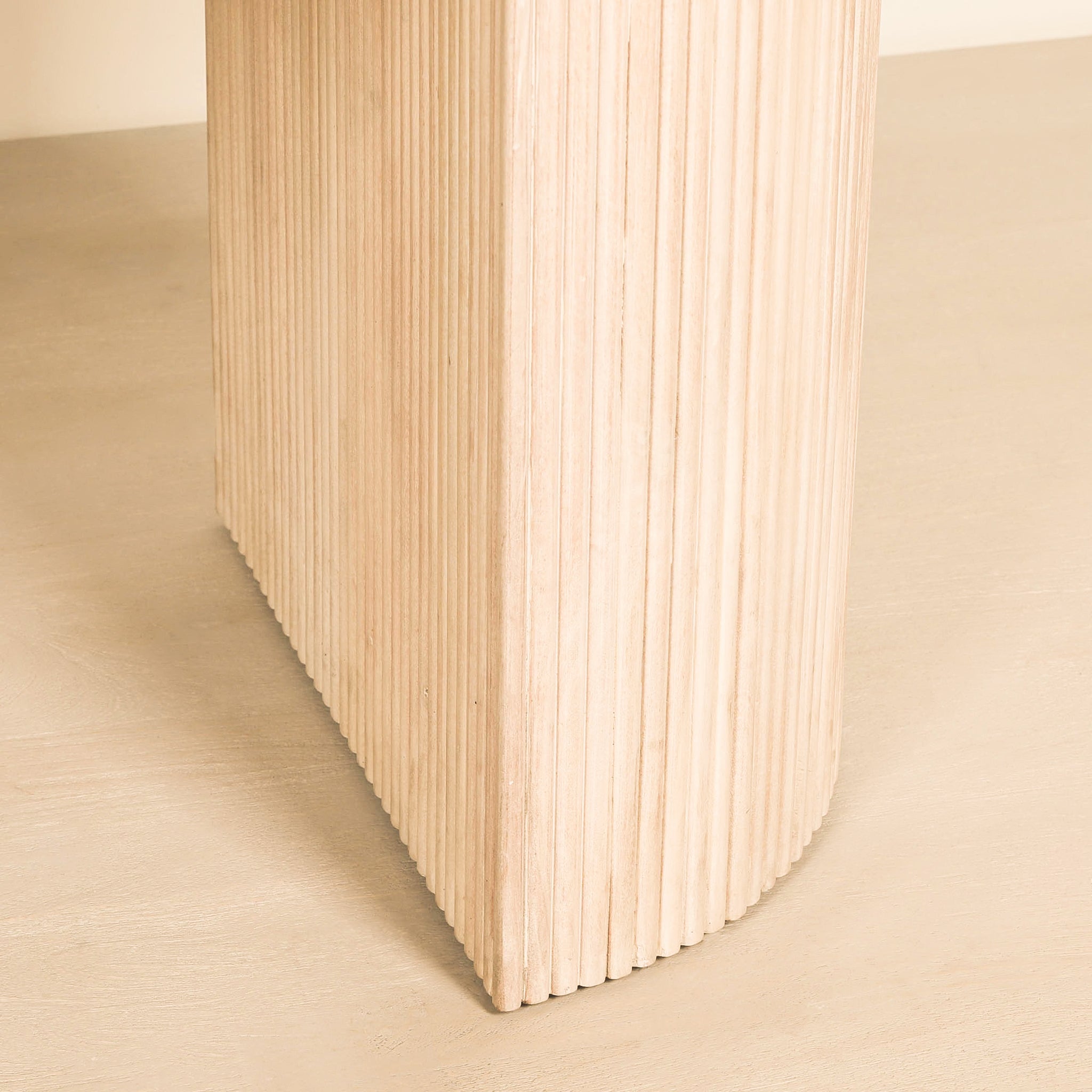 Close-up of the sculptural fluted pedestal base on the Camille Fluted Acacia Wood Oval 6 Seater Dining Table, showcasing the textured ribbed acacia wood, rounded profile and elegant bleached washed wood finish.