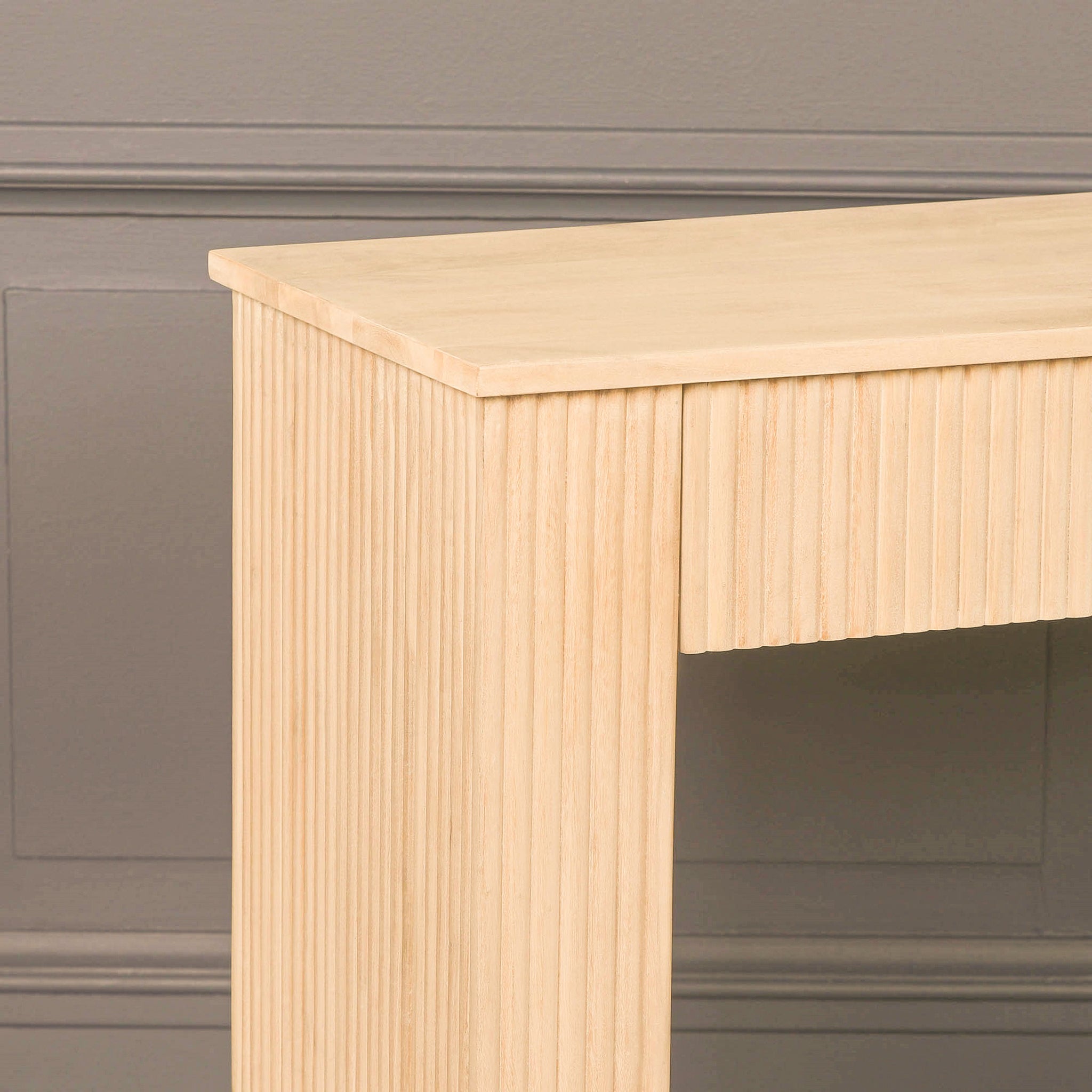 Close-up of the Camille fluted acacia wood console table showing the light bleached washed tabletop, vertical grooved detailing and substantial rectangular side leg.