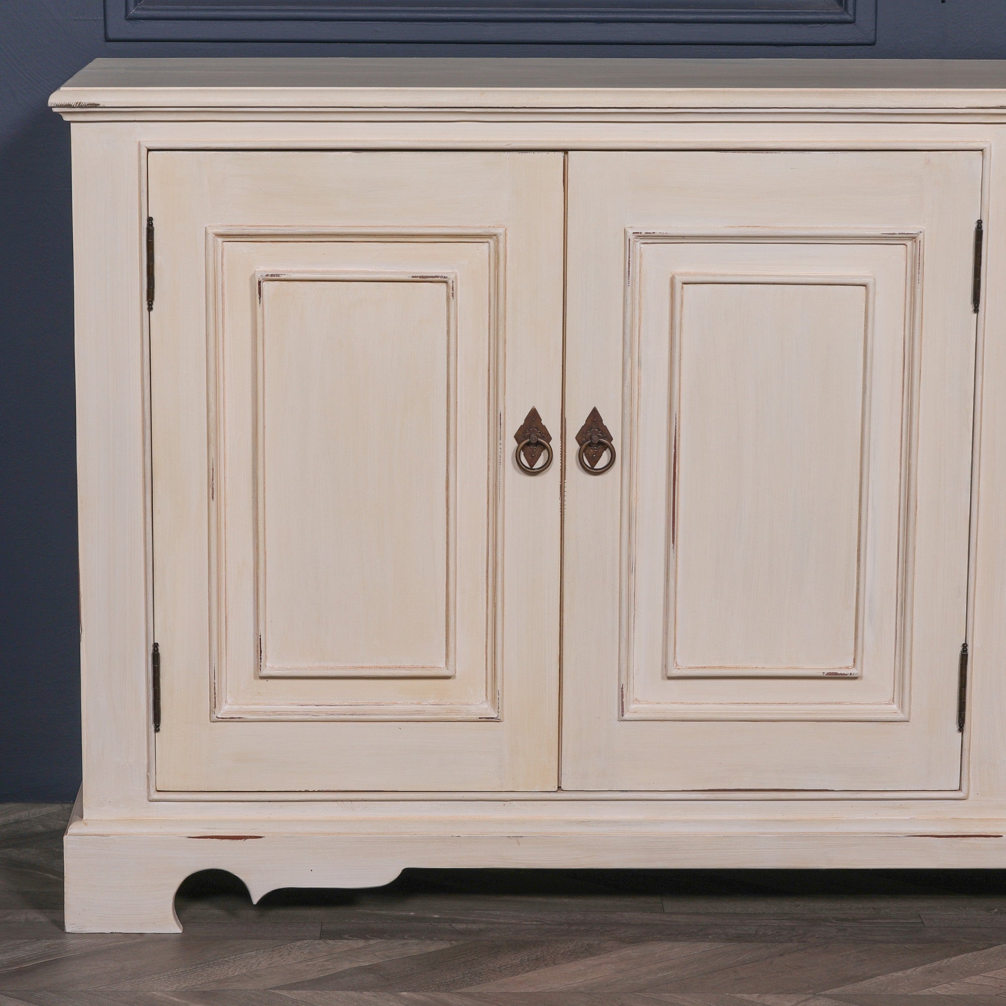 Detailed view of the Camille Four Door Classical Sideboard showcasing traditional panelled cupboard doors, aged white mahogany finish, antique metal ring pull handles and handcrafted furniture detailing.