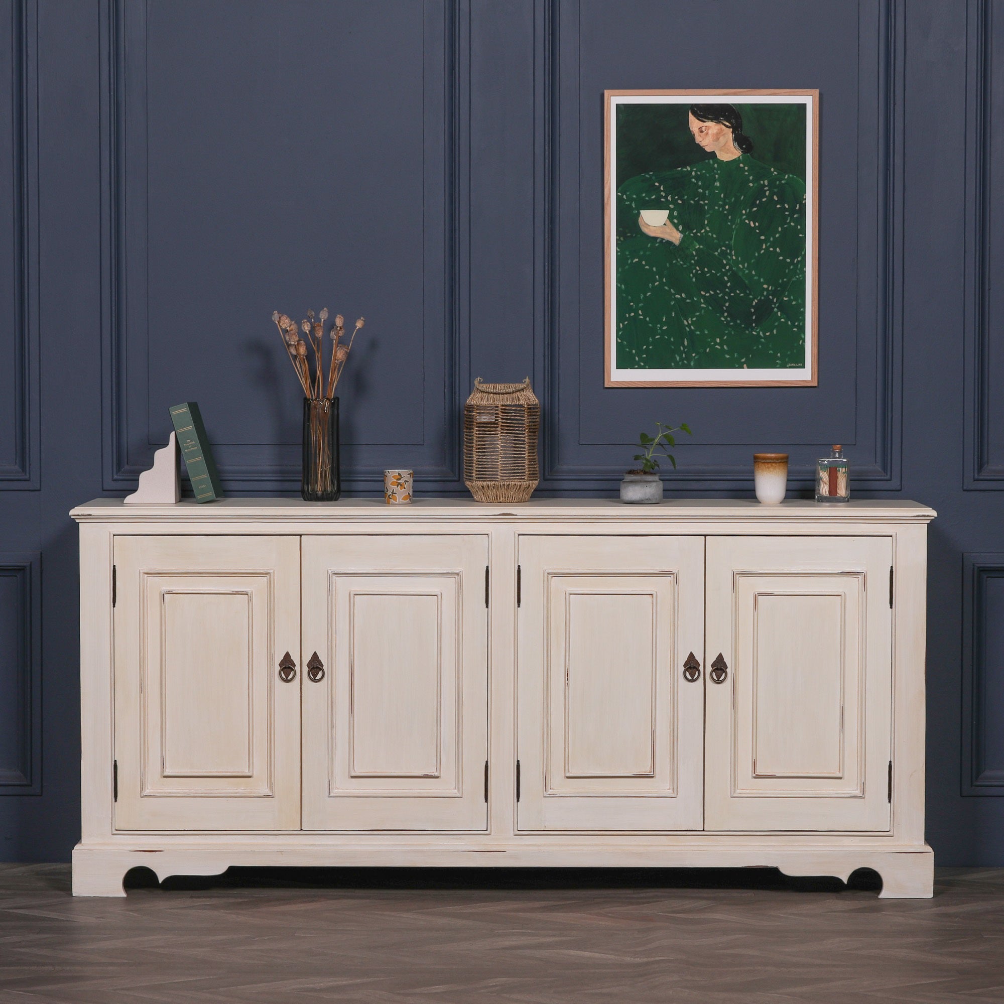 Camille Four Door Classical Sideboard in an aged white mahogany finish styled in a luxury living room, featuring four cupboard doors, spacious concealed storage and timeless French country inspired craftsmanship.