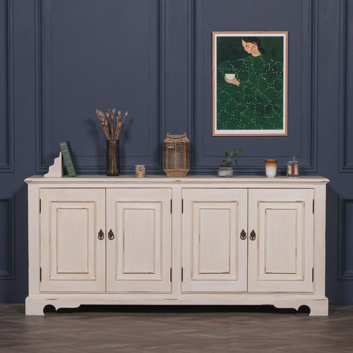 Camille Four Door Classical Sideboard in an aged white mahogany finish styled in a luxury living room, featuring four cupboard doors, spacious concealed storage and timeless French country inspired craftsmanship.