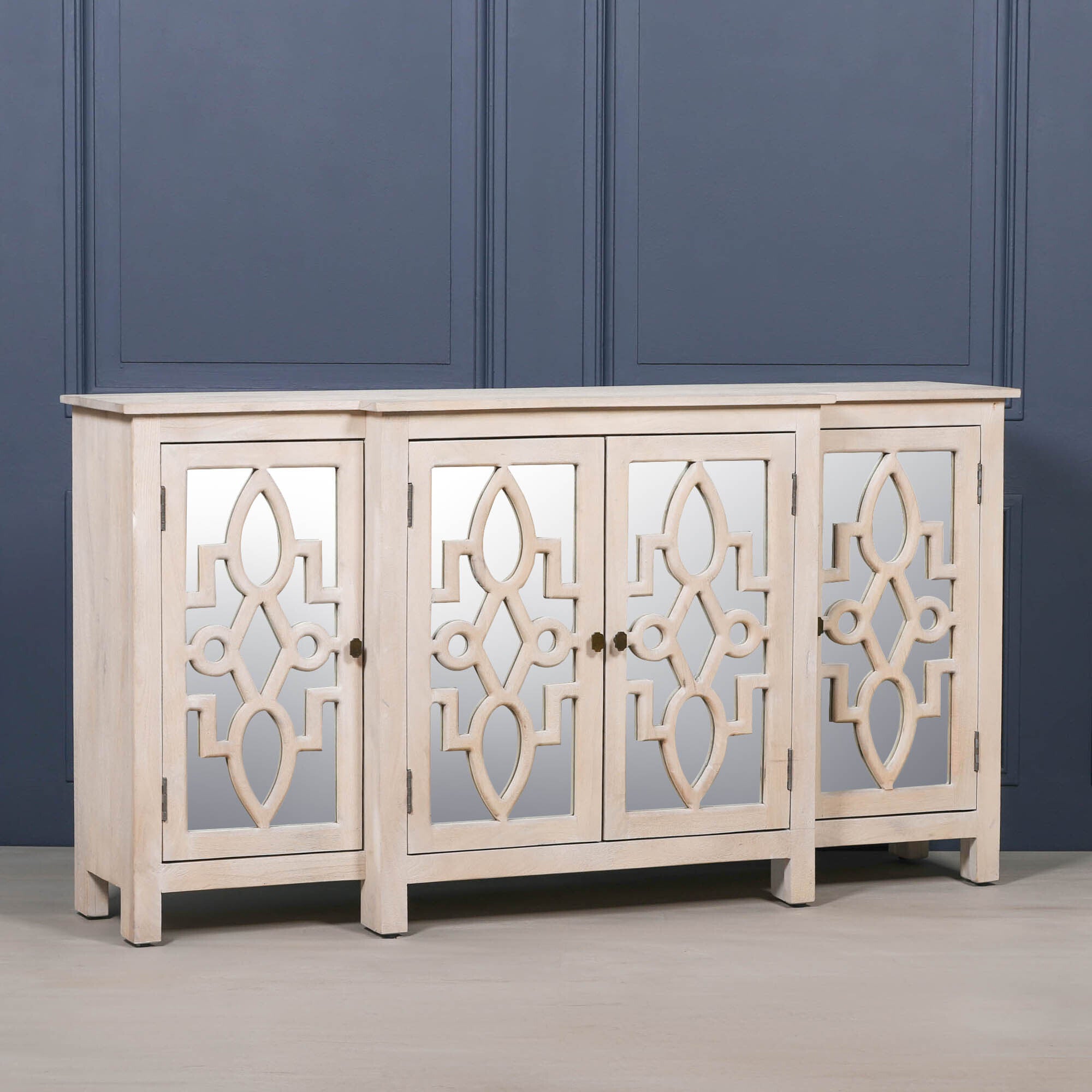 Perspective view of the Camille Four Door Mirrored Sideboard crafted from bleached mango wood with mirrored cabinet doors, contemporary styling and generous concealed storage.