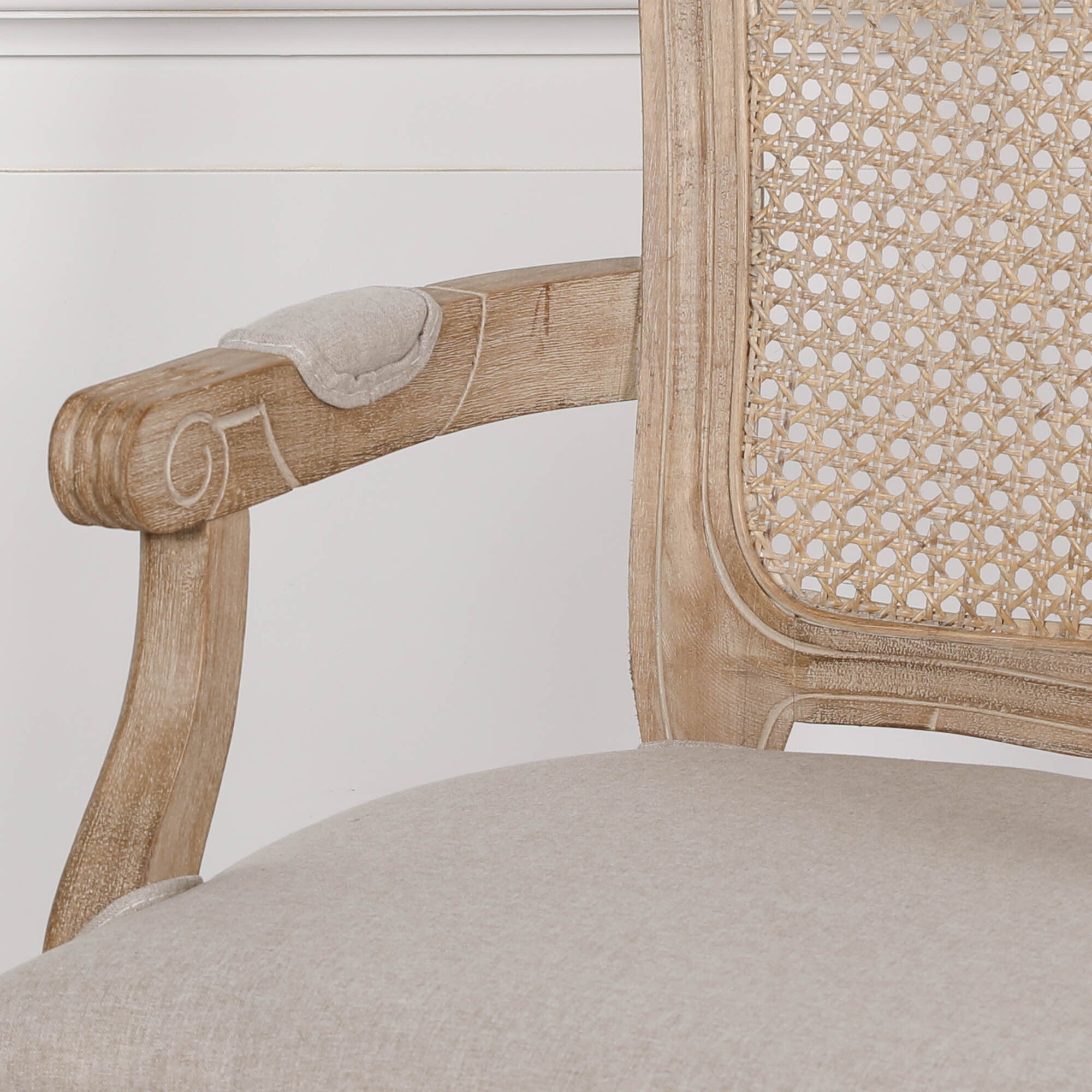 Close-up of Camille dining armchair showing carved birch wood arm, cane back and linen upholstery on a white background