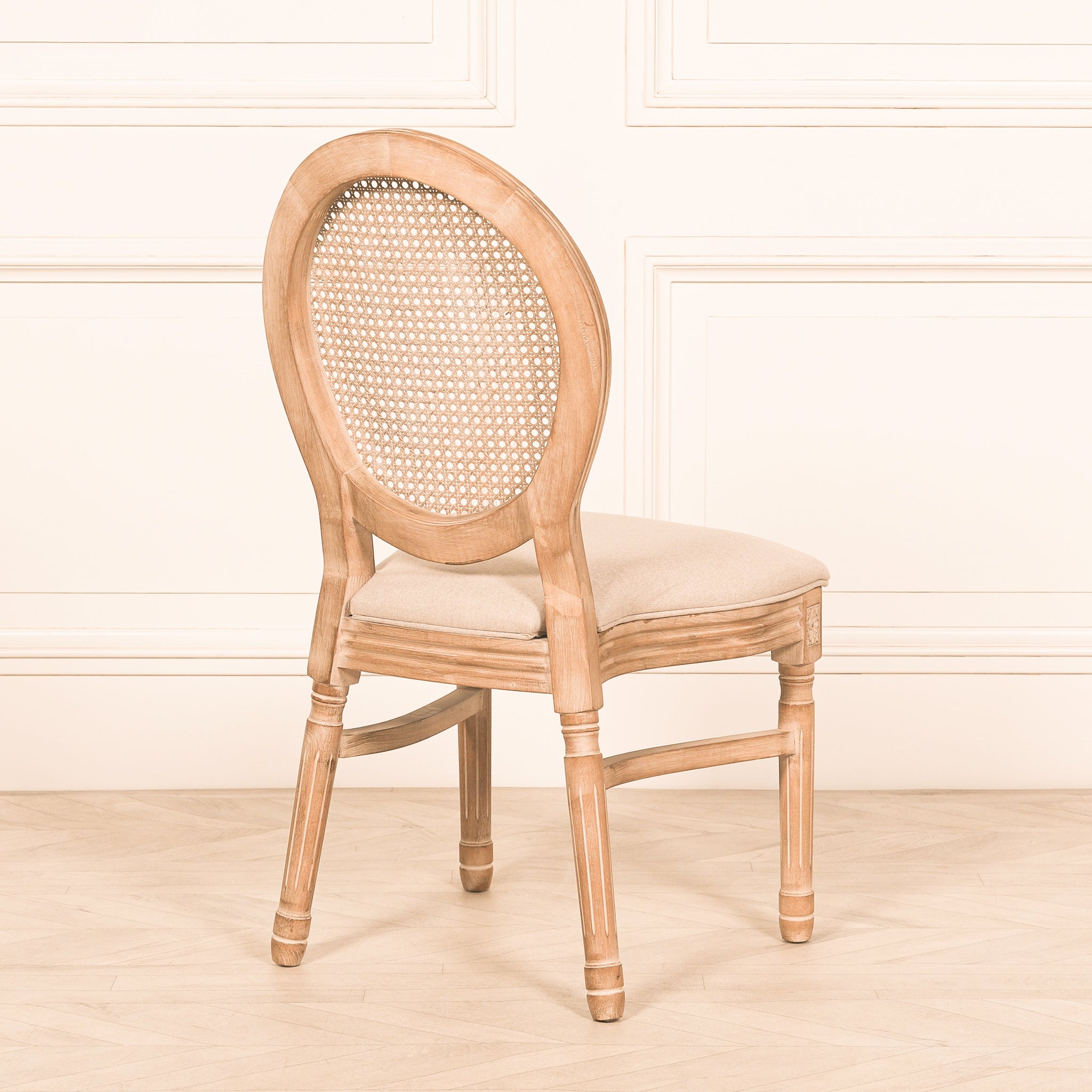 Rear angled view of the Camille French Louis Linen Upholstered Dining Chair highlighting the hand-carved wooden frame, oval cane back, linen upholstered seat and timeless French country styling.