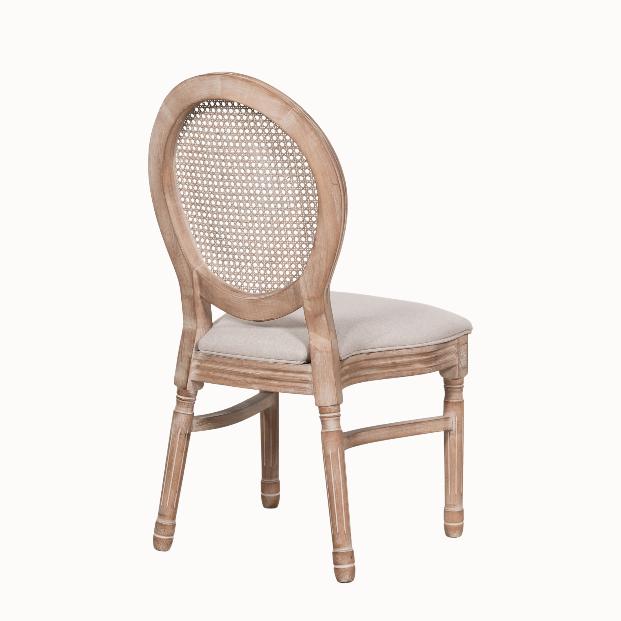 Rear angled view of Camille French Louis dining chair with carved wooden frame and cane back on white.