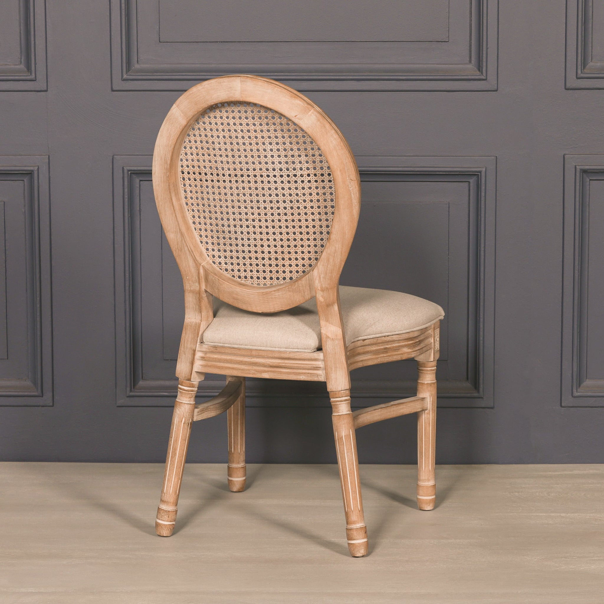 Rear view of the Camille French Louis Linen Upholstered Dining Chair showcasing the curved carved wooden frame, oval woven rattan backrest and elegant French-inspired craftsmanship.